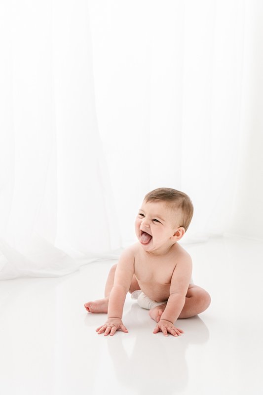  A baby crawls around in a white studio laughing captured by Nicole Hawkins Photography. crawling baby New Jersey Photography of Children #sixmonthbabyportraits #NJPhotographer #NicoleHawkinsPhotography #NicoleHawkinsBabies #BabyStudioPhotography    