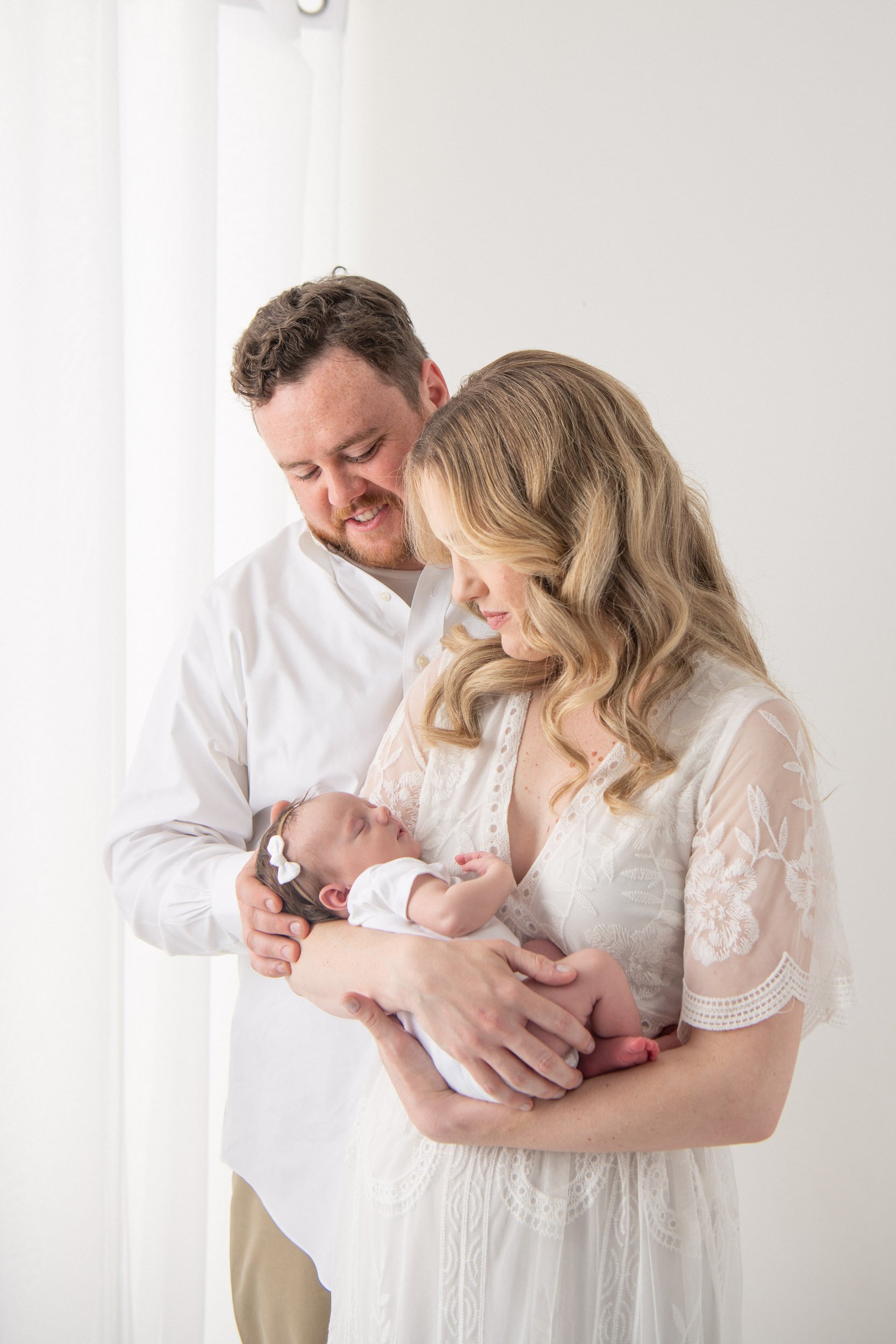  A portrait of a mother and father looking lovingly at their newborn baby by Nicole Hawkins Photography. family of three newborn family #NicoleHawkinsPhotography #NicoleHawkinsNewborns #StudioPhotography #NewYorkPhotographer #NJphotographers #newborn