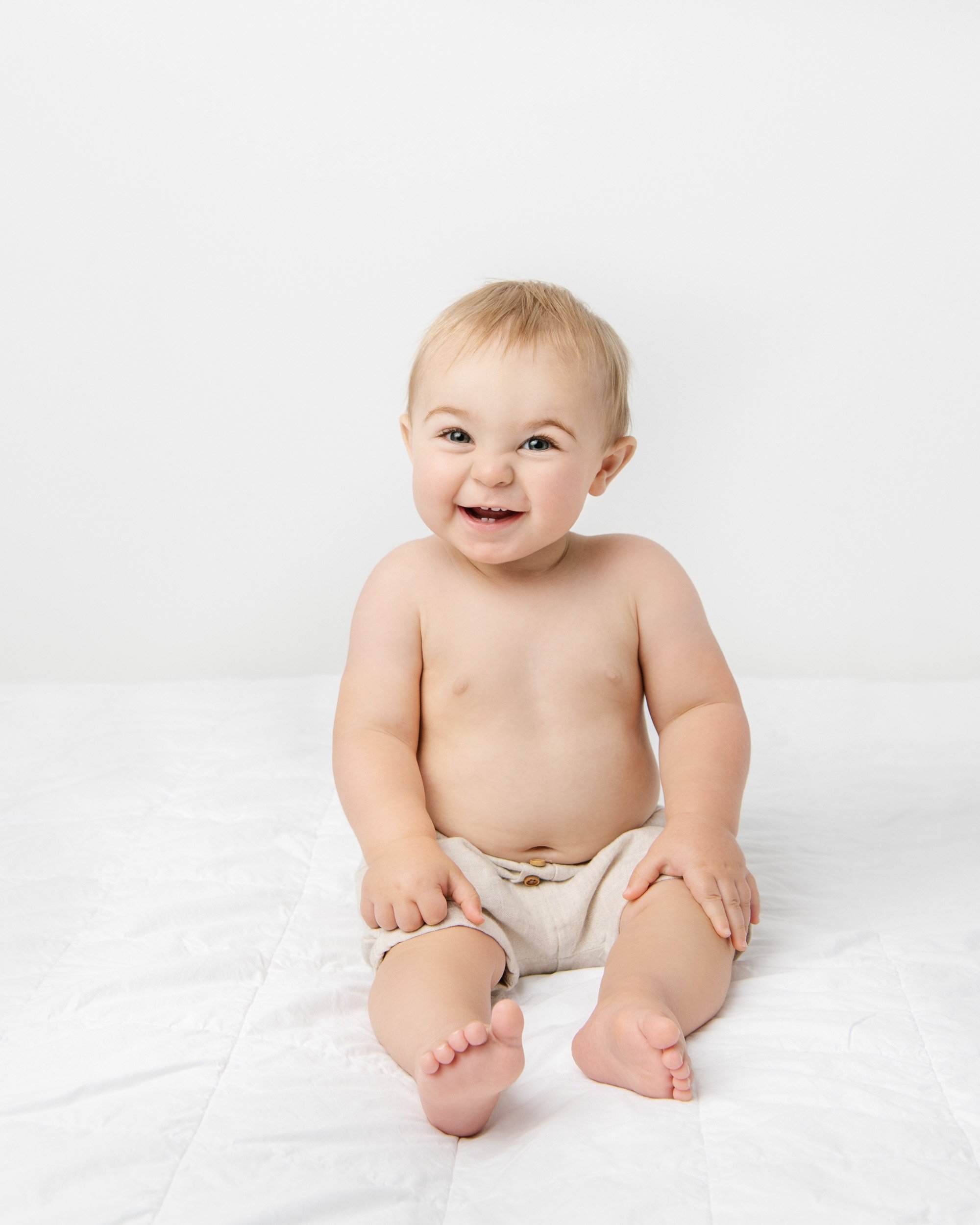  Nicole Hawkins Photography captures a portrait of a chunky little boy smiling in an all-white studio. chunky baby #NicoleHawkinsPhotography #NicoleHawkinsBabies #BirthdayStudioPhotography #smashcake #firstbirthday #studiobabiesandchildren 