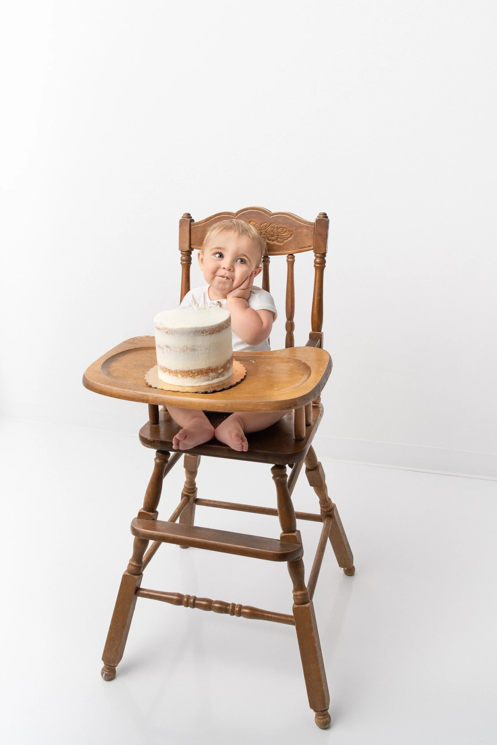  First birthday photo with a baby in an antique high chair by Nicole Hawkins Photography. antique high chair smash cake #NicoleHawkinsPhotography #NicoleHawkinsBabies #BirthdayStudioPhotography #smashcake #firstbirthday #studiobabiesandchildren 