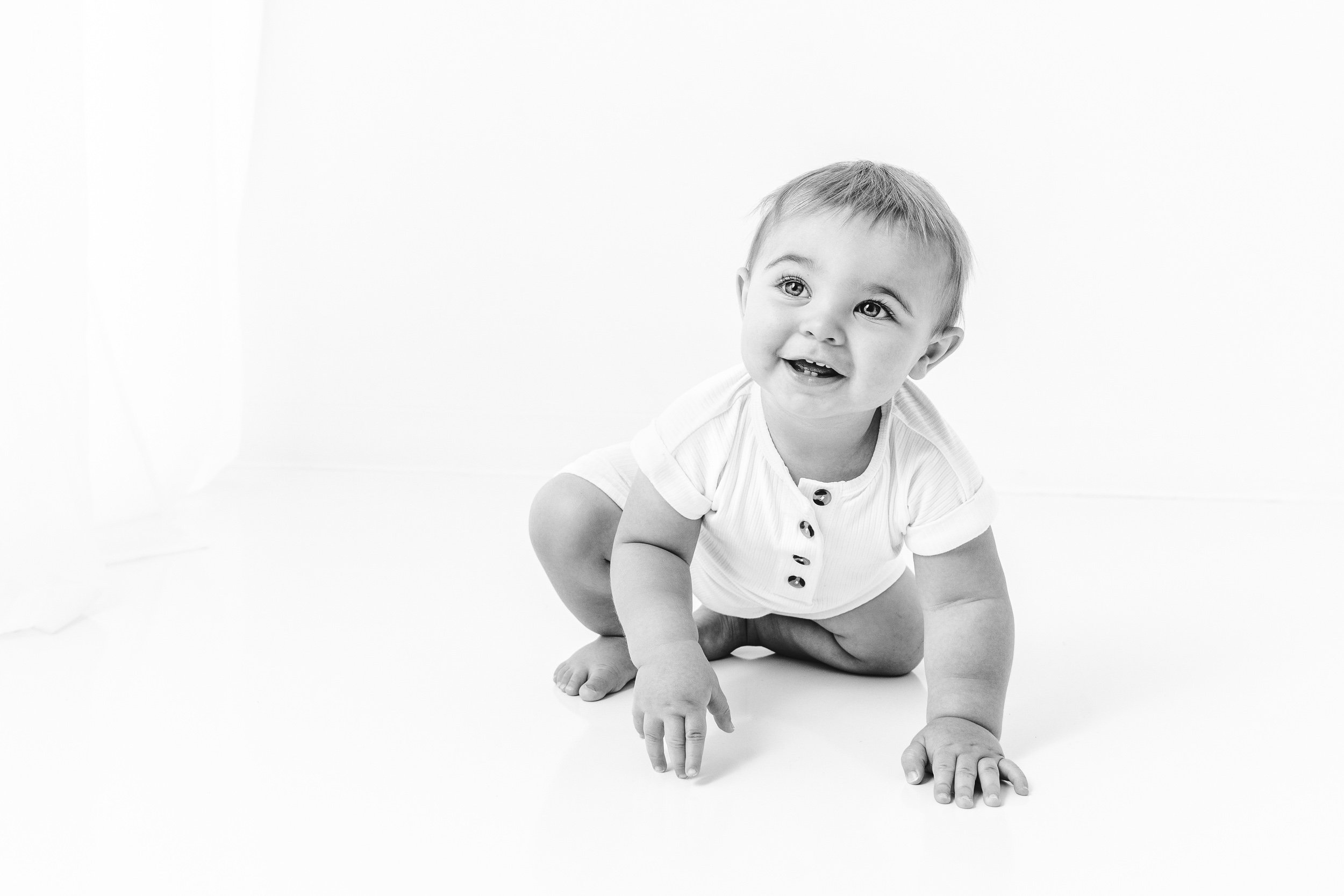  Little boy crawling around a studio during a children's session with Nicole Hawkins Photography. crawling baby white romper #NicoleHawkinsPhotography #NicoleHawkinsBabies #BirthdayStudioPhotography #smashcake #firstbirthday #studiobabiesandchildren 