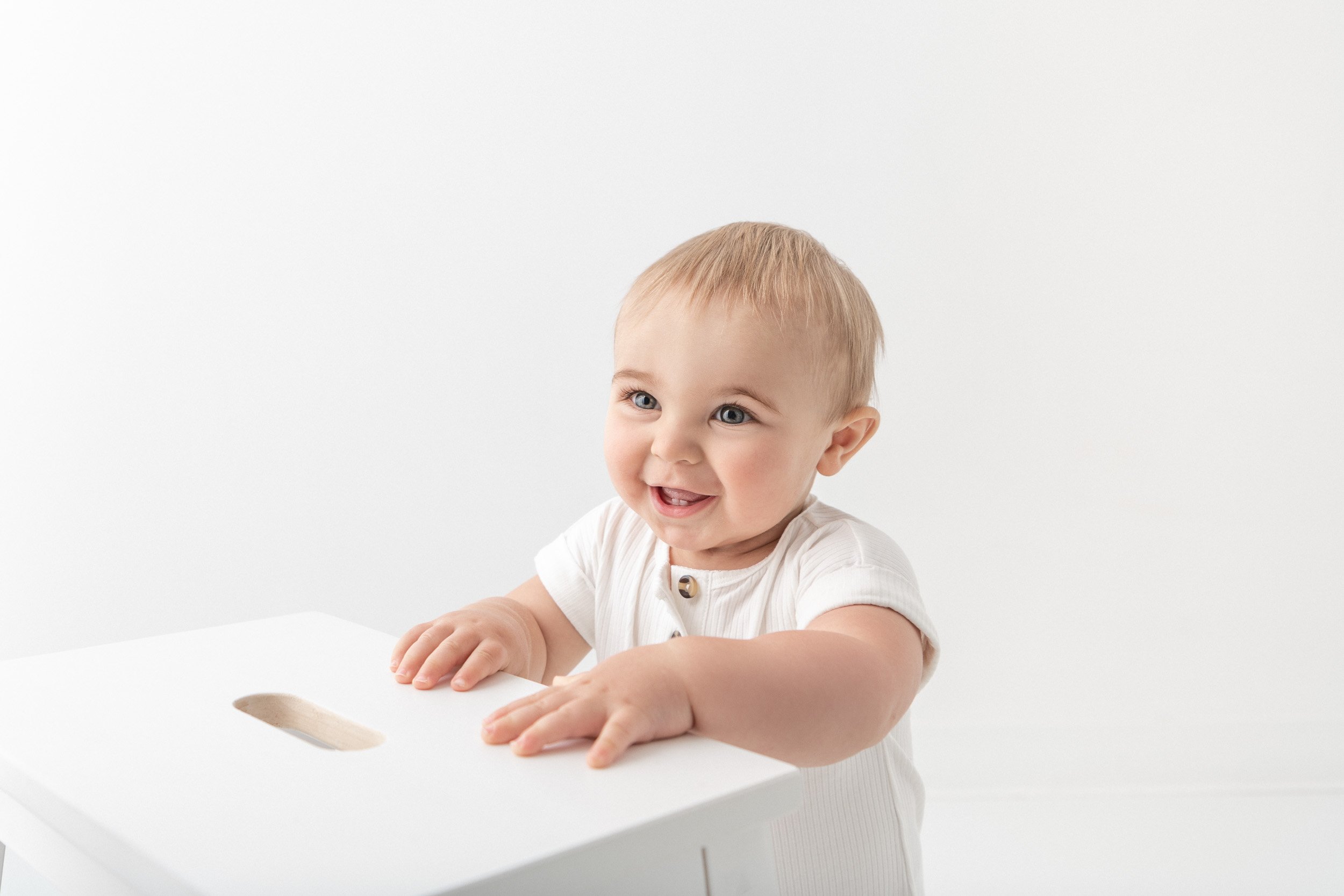  During a birthday photography session, a baby plays on a table by Nicole Hawkins Photography. action baby shots bday #NicoleHawkinsPhotography #NicoleHawkinsBabies #BirthdayStudioPhotography #smashcake #firstbirthday #studiobabiesandchildren 
