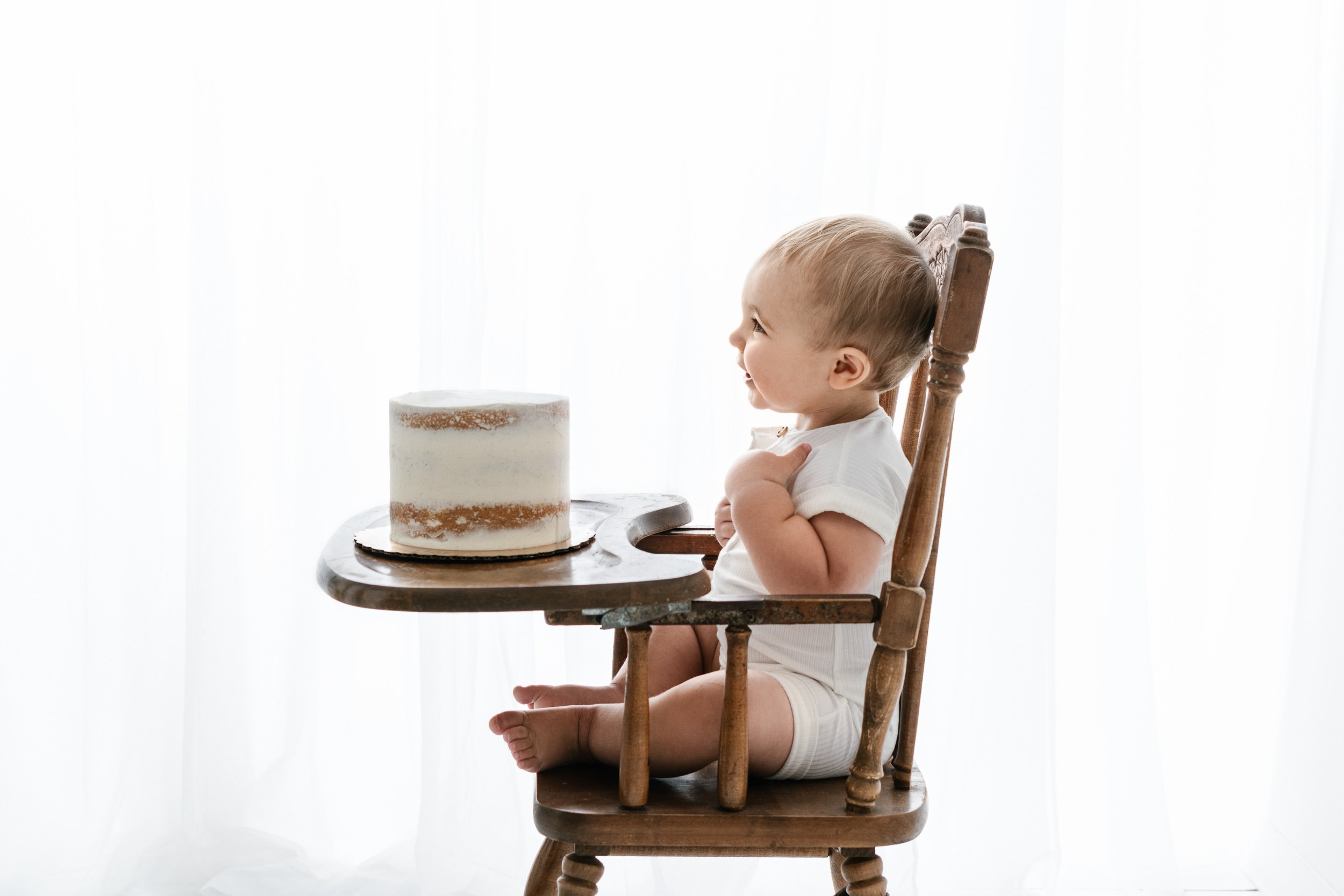  Portrait of a baby in a high chair during his birthday session with Nicole Hawkins Photography. high chair cake #NicoleHawkinsPhotography #NicoleHawkinsBabies #BirthdayStudioPhotography #smashcake #firstbirthday #studiobabiesandchildren 