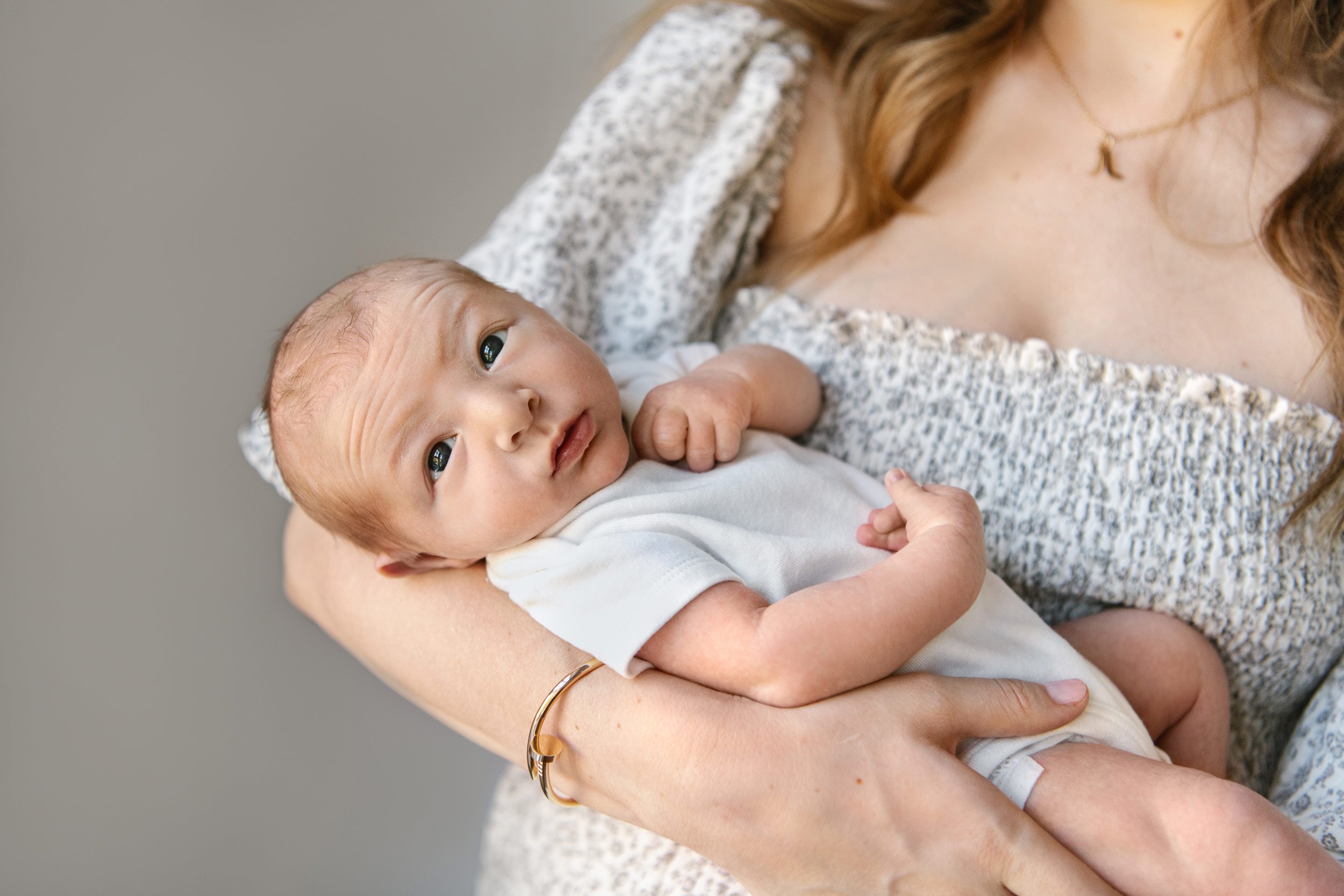  Newborn baby being held in his mother's arms by NJ photographer Nicole Hawkins Photography. newborn photographers NJ #NicoleHawkinsPhotography #InHomeNewborn #JerseyShoreNewborns #MontclairPhotographers #NewbornPhotography #baby #newborn 