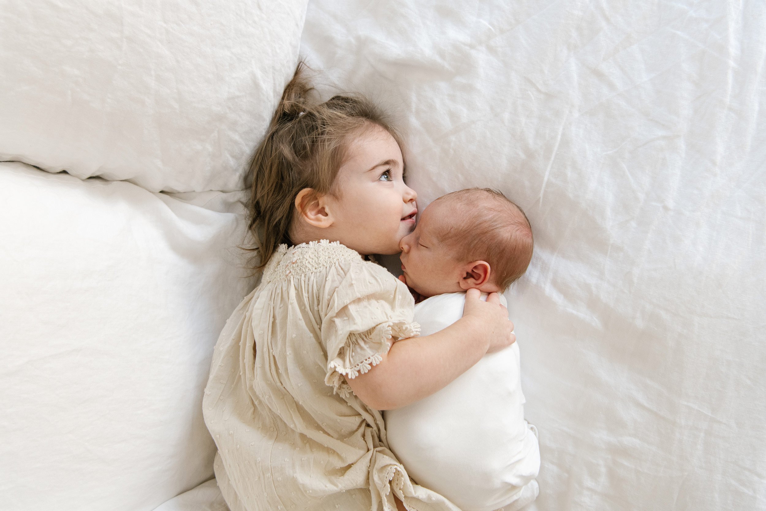  A toddler baby girl snuggles her newborn baby brother captured by Nicole Hawkins Photography. sibling newborn pic #NicoleHawkinsPhotography #InHomeNewborn #JerseyShoreNewborns #MontclairPhotographers #NewbornPhotography #baby #newborn 