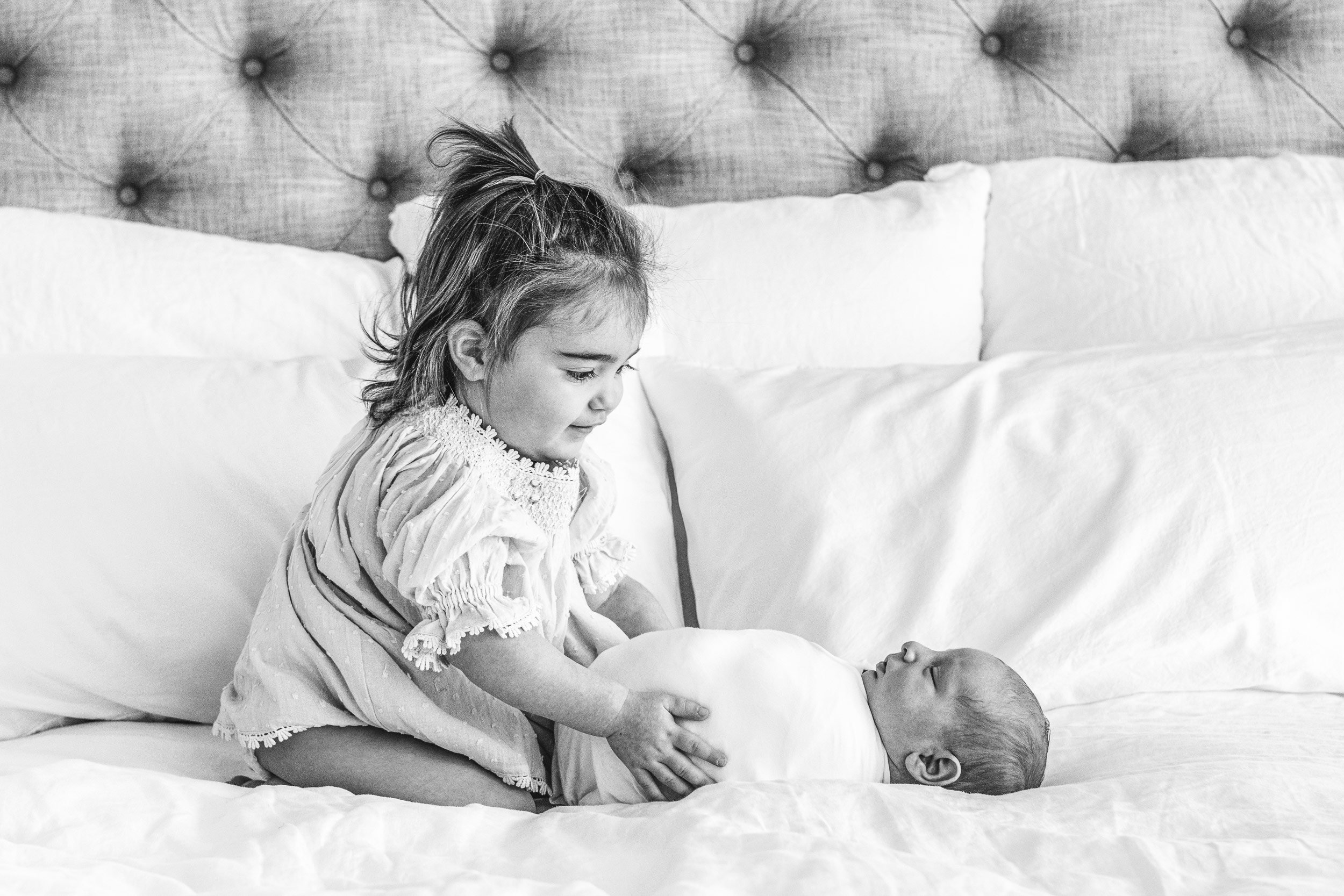  Nicole Hawkins Photography captures a stunning black and white portrait of two little siblings on a bed. baby and sister #NicoleHawkinsPhotography #InHomeNewborn #JerseyShoreNewborns #MontclairPhotographers #NewbornPhotography #baby #newborn 