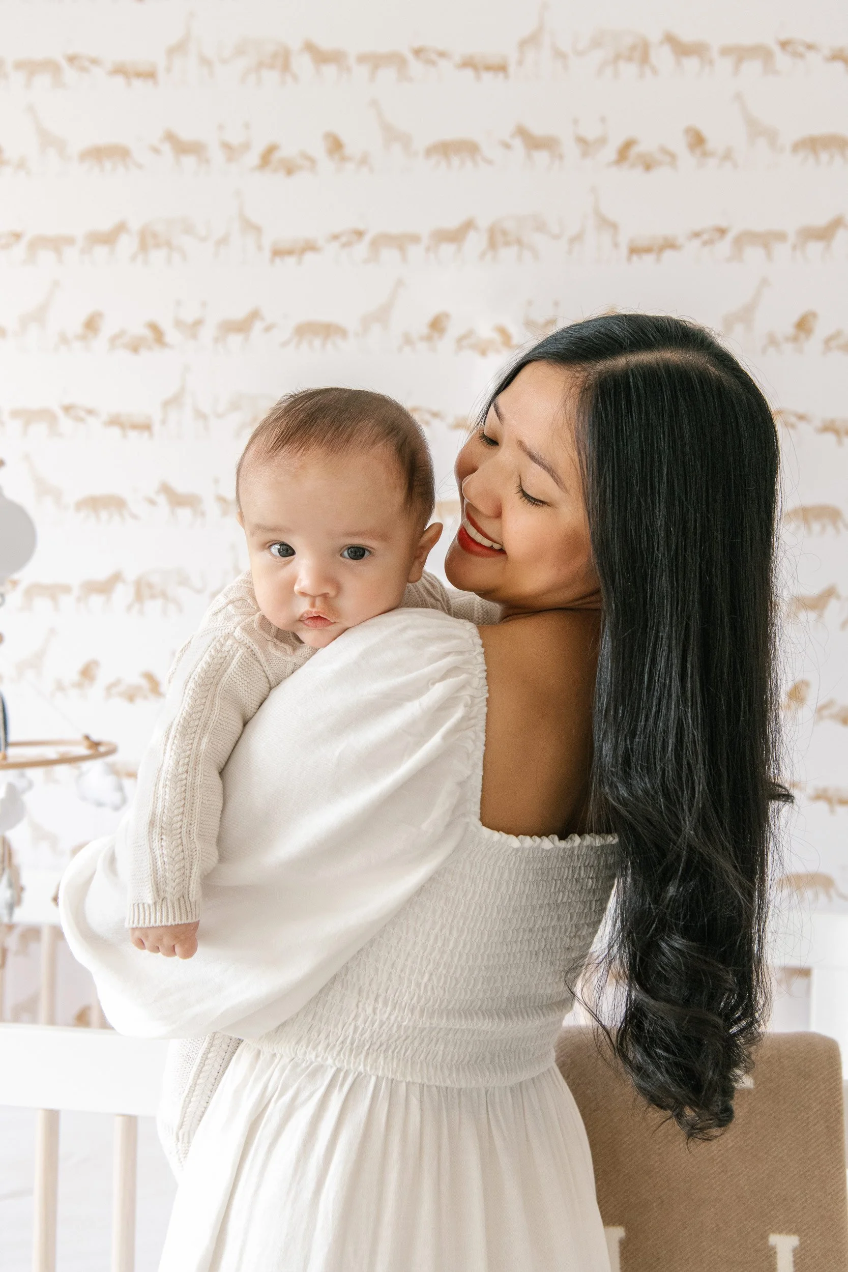  A mother holding her baby in his monochromatic jungle nursery captured by Nicole Hawkins Photography. baby photographer #NicoleHawkinsPhotography #InHomeNewborns #NurseryNewborns #NYCbabyphotography #babyportraits #ZooNursery #familyportraits 