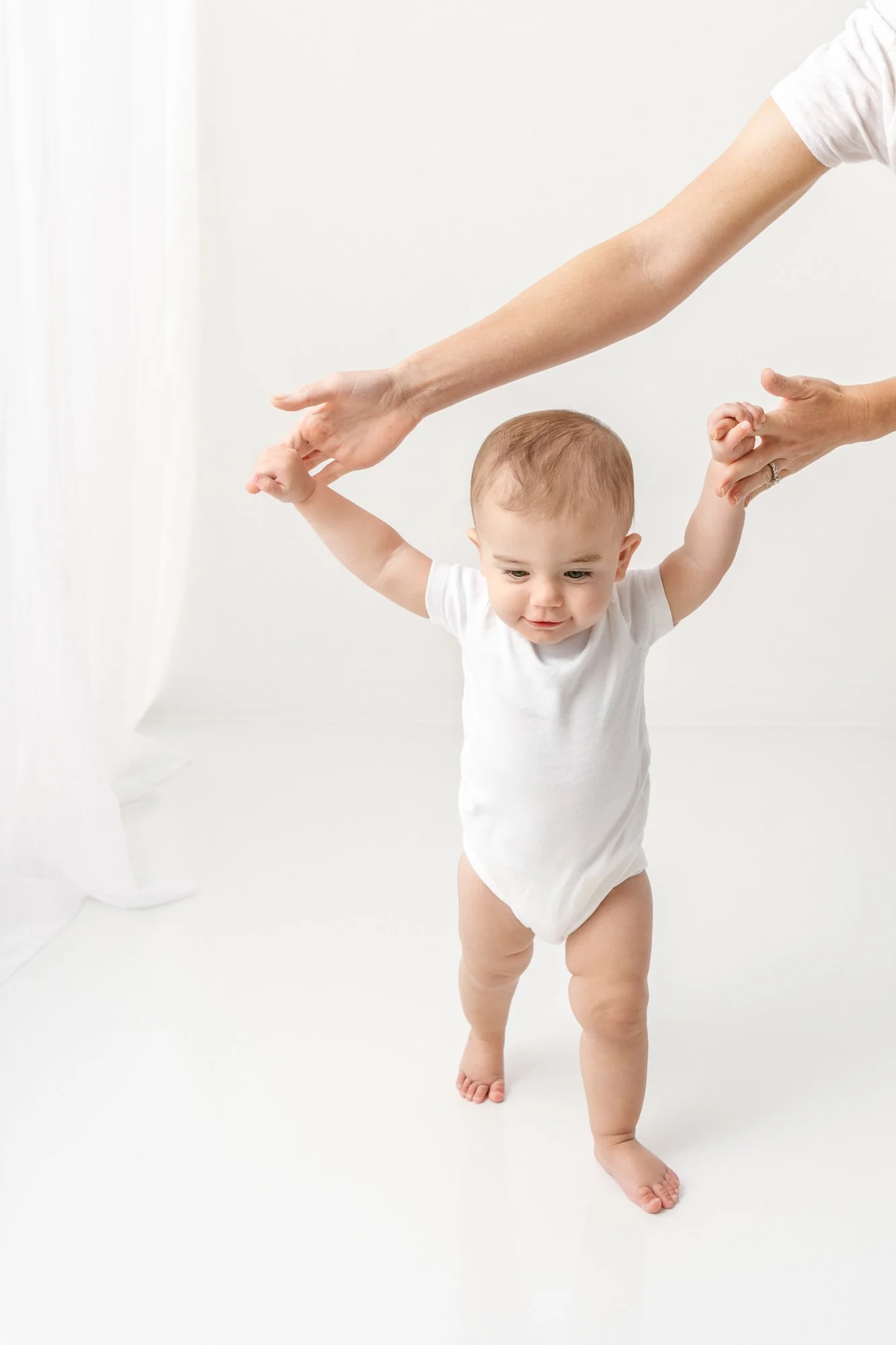  A mother holds her baby’s fingers and helps her walk around a studio captured by Nicole Hawkins Photography. walking #NicoleHawkinsPhotography #firstbirthday #babyportraits #NJphotographers #lifestylephotography #studiobabies #childrenphotography 