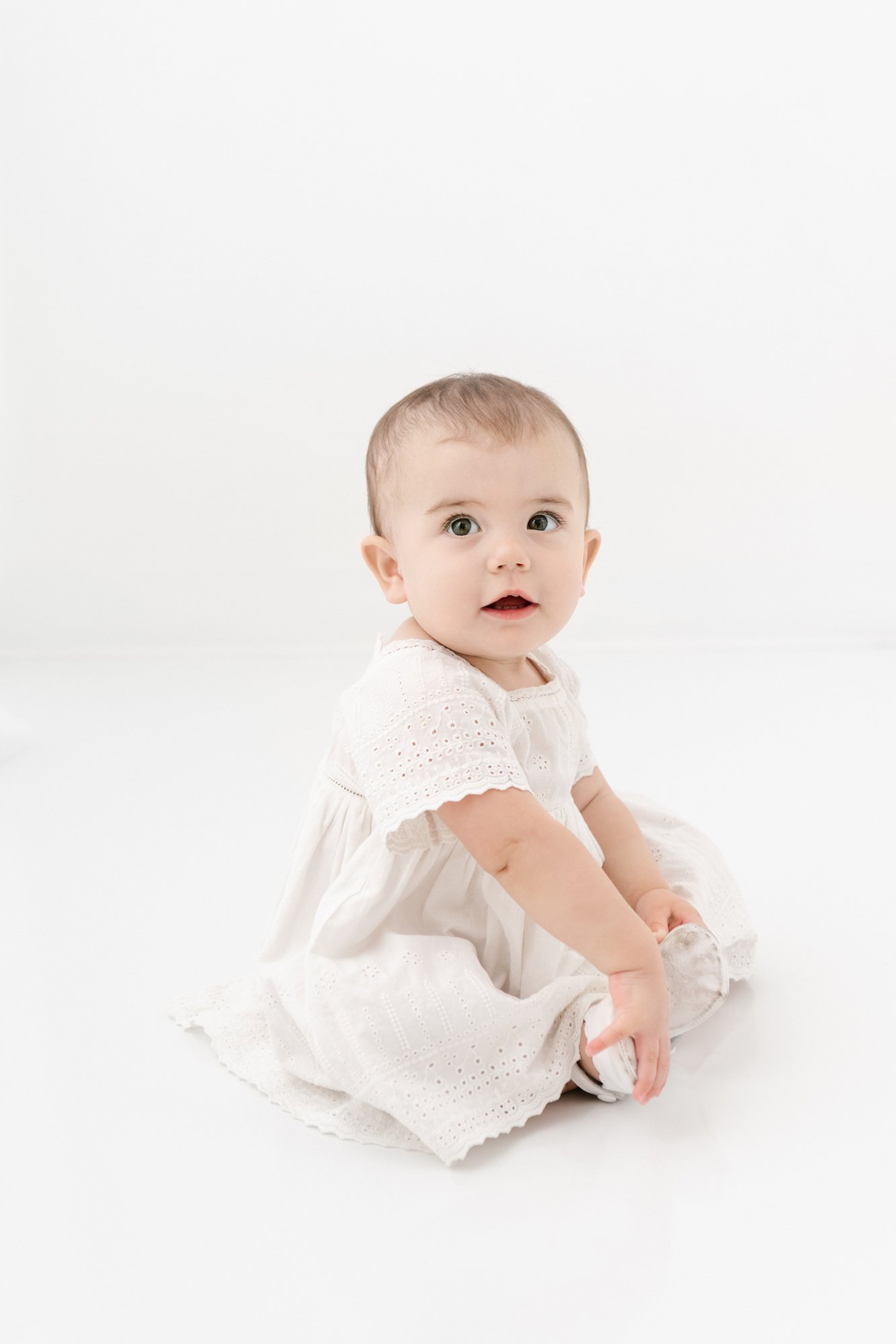  In a studio in NJ, a baby girl sits in an antique gown and smiles captured by Nicole Hawkins Photography. sitting baby #NicoleHawkinsPhotography #firstbirthday #babyportraits #NJphotographers #lifestylephotography #studiobabies #childrenphotography 