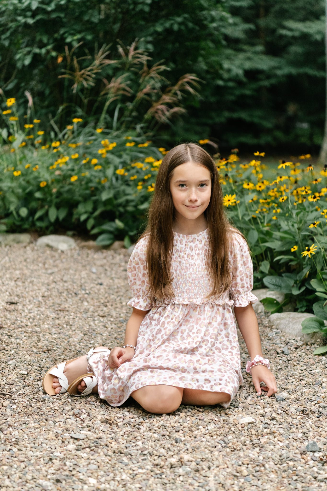  A young girl in a floral dress poses for her portrait in front of yellow flowers by Nicole Hawkins Photography. girl in floral dress #NicoleHawkinsPhotography #NicoleHawkinsFamilyPortrait #NicoleHawkinsSenior #NJPortraits #siblingportrait 
