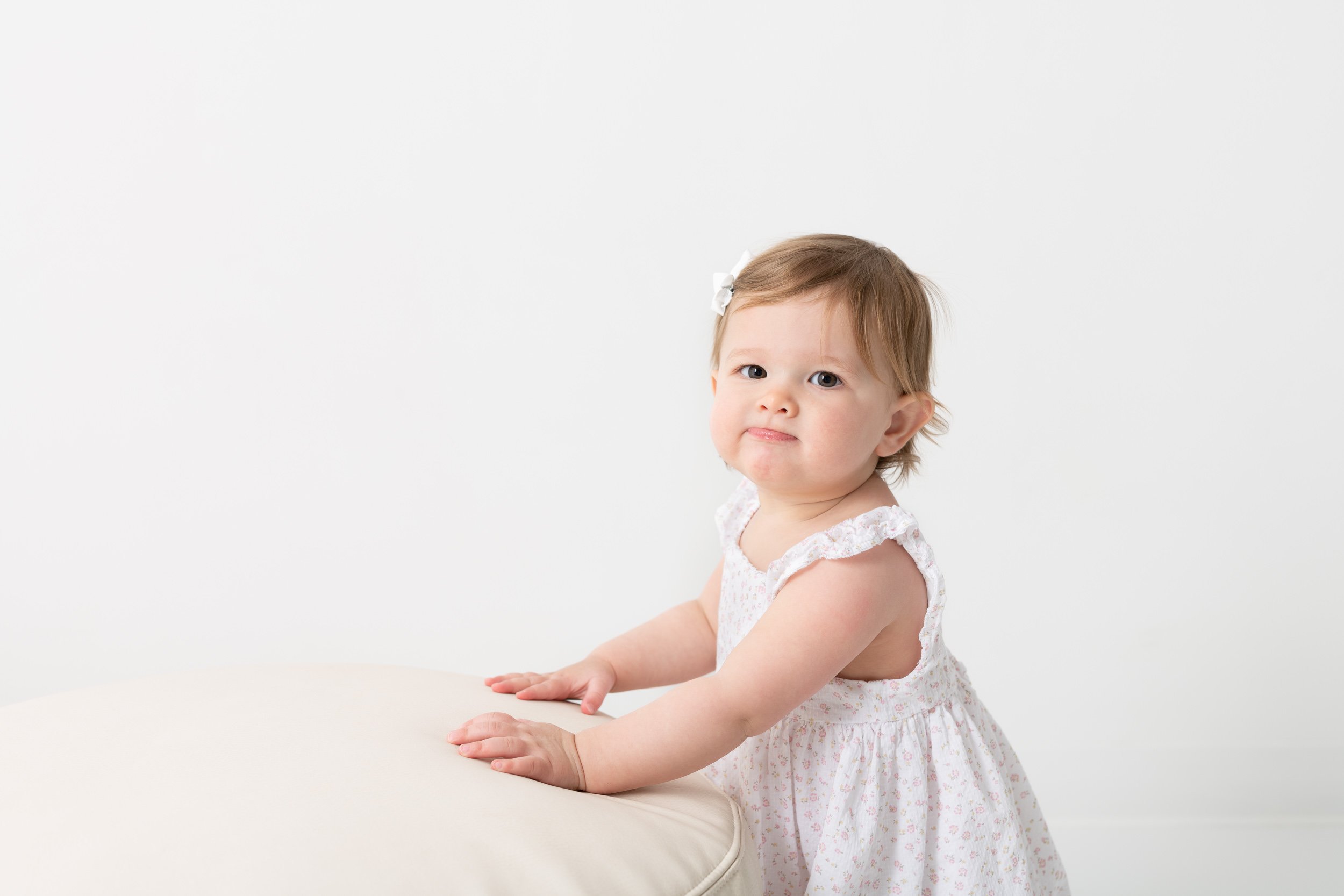  A first birthday portrait was taken of a little girl in a white dress by Nicole Hawkins Photography. little girl silly faces #NicoleHawkinsPhotography #NicoleHawkinsBabies #studiochildren #firstbirthday #studiophotography #girlsbirthdayportraits 