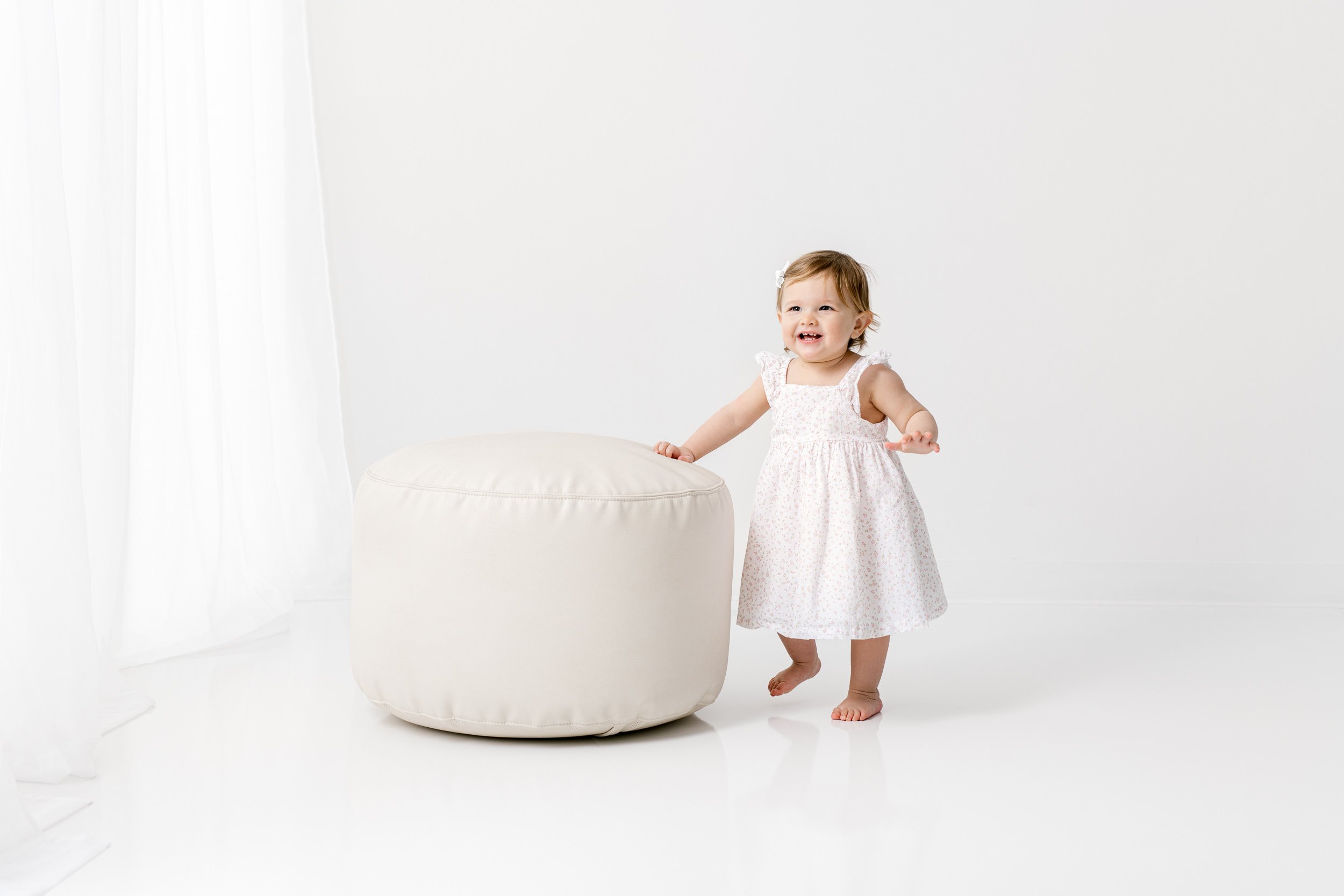  A little girl walking around a white studio during a birthday session with Nicole Hawkins Photography. laughing baby portrait #NicoleHawkinsPhotography #NicoleHawkinsBabies #studiochildren #firstbirthday #studiophotography #girlsbirthdayportraits 