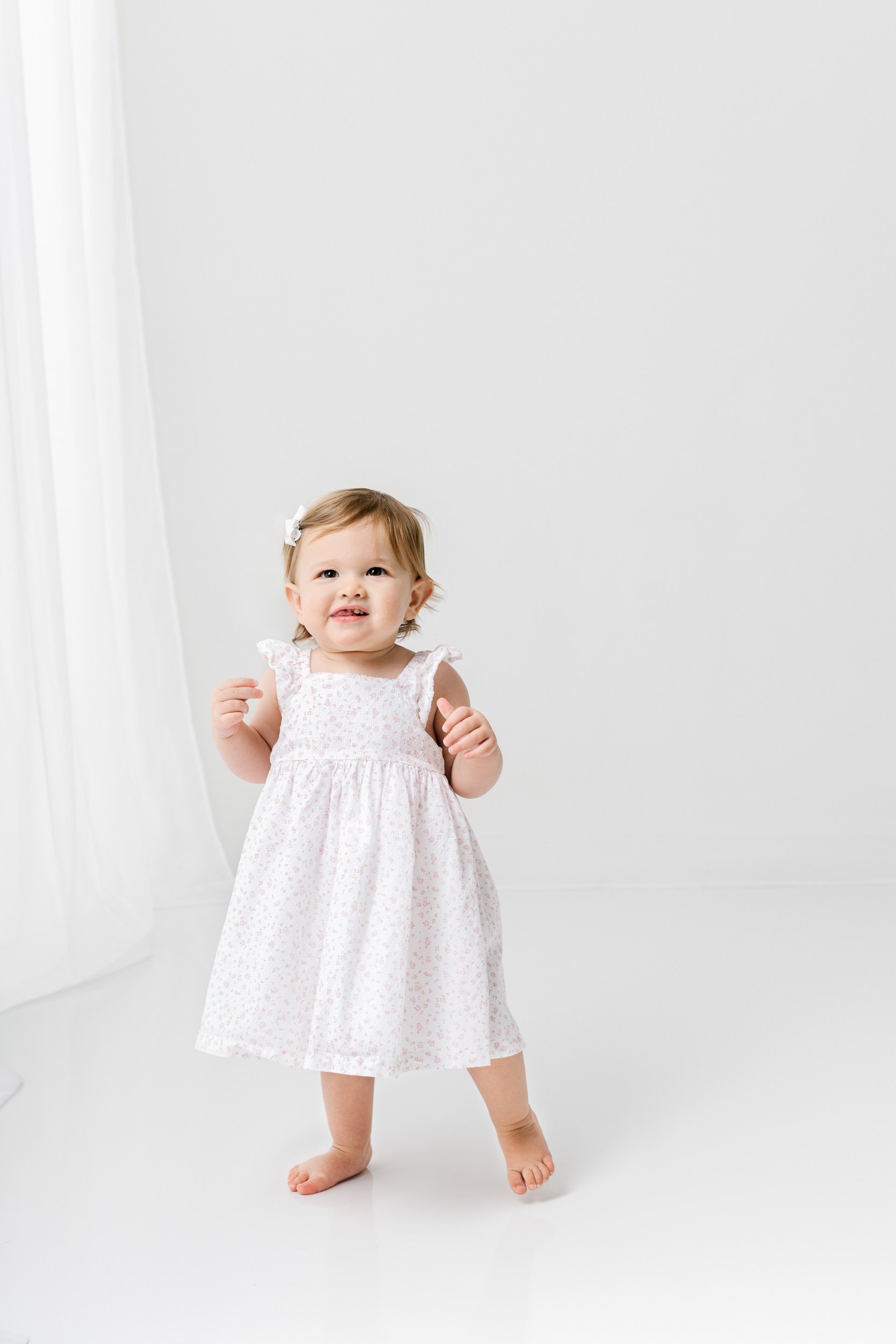  A studio portrait of a baby girl in a white floral dress on her first birthday by Nicole Hawkins Photography. baby girl #NicoleHawkinsPhotography #NicoleHawkinsBabies #studiochildren #firstbirthday #studiophotography #girlsbirthdayportraits 