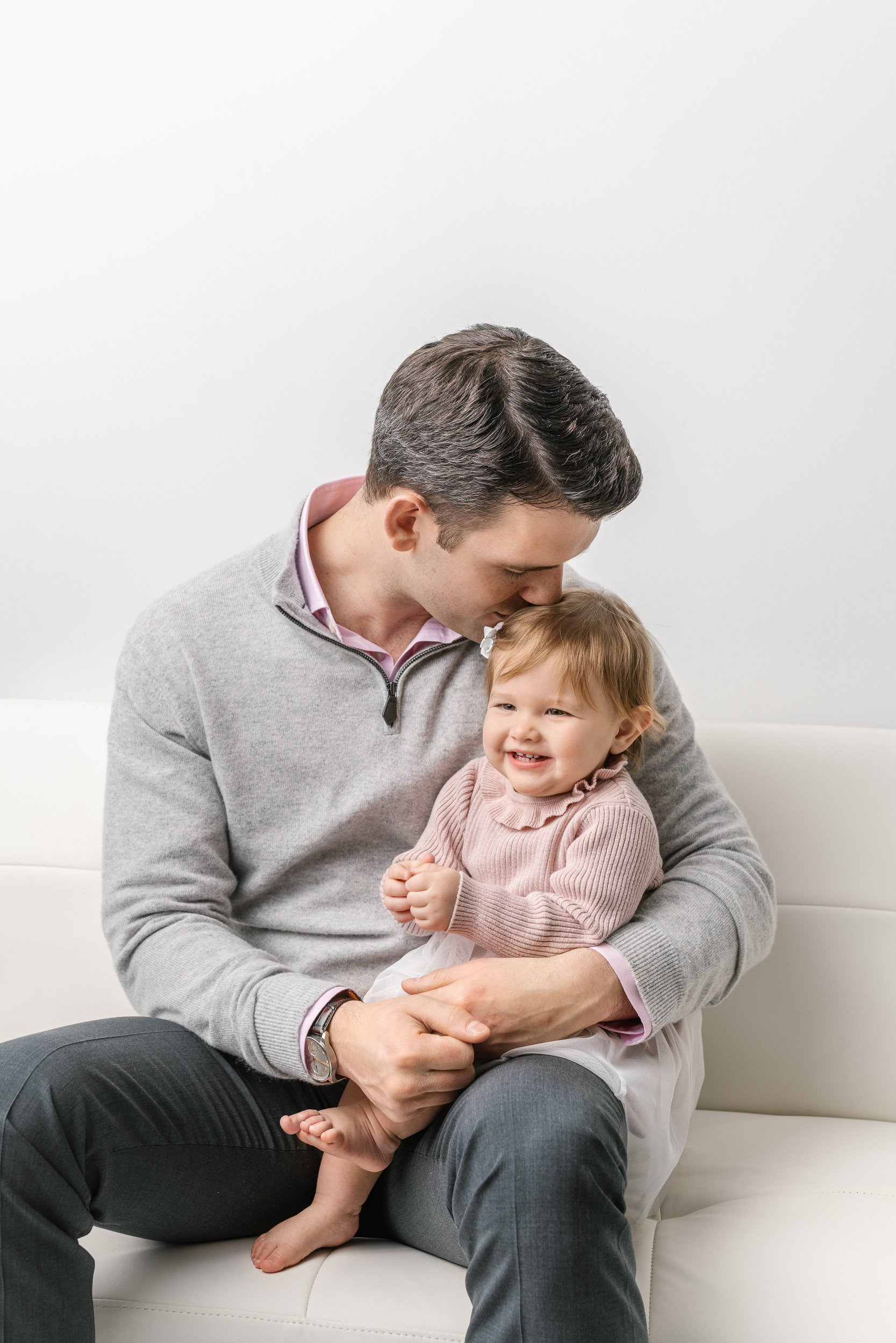  A father to a little girl kisses the top of her head at an NJ studio by Nicole Hawkins Photography. father's love baby girl #NicoleHawkinsPhotography #NicoleHawkinsBabies #studiochildren #firstbirthday #studiophotography #girlsbirthdayportraits 