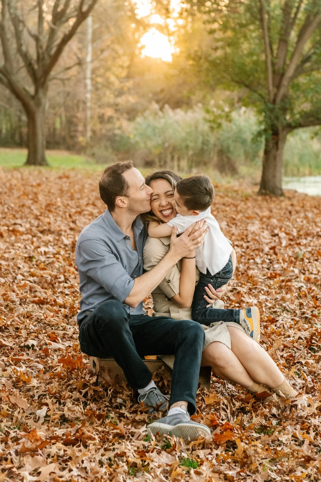  Family photographer Nicole Hawkins Photography captures a portrait of a father and son kissing the mother. two boys kissing mom #NicoleHawkinsPhotography #NicoleHawkinsFamilies #fallfamilyphotos #NorthernNewJerseyPhotography #outdoorfamilyportraits 