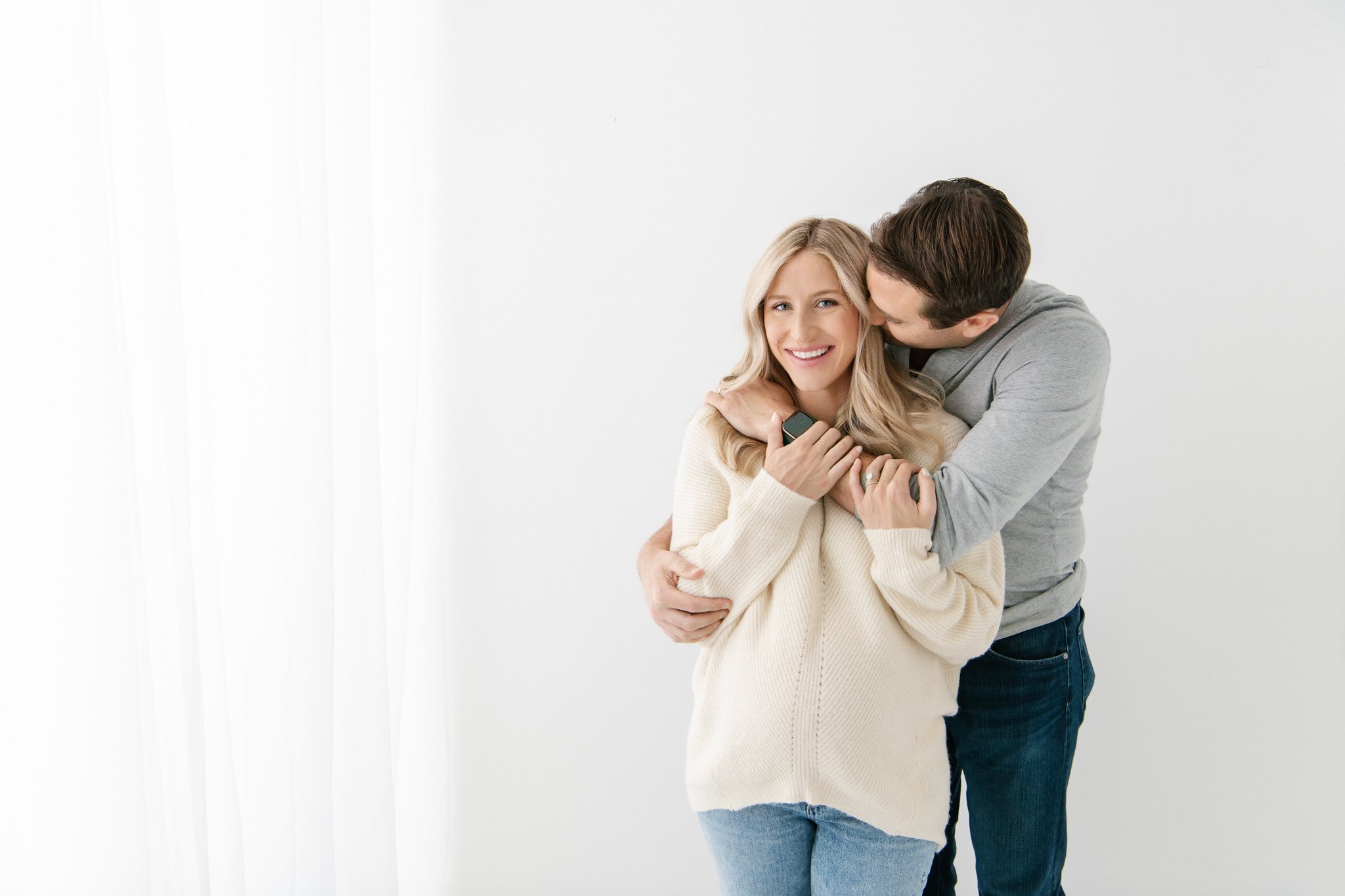  A husband hugs his pregnant wife in a bright studio captured by Nicole Hawkins Photography on the East Coast. growing family #NicoleHawkinsPhotography #NicoleHawkinsMaternity #Studiomaternityportraits #NewJerseymaternity #NewYorkMaternity 
