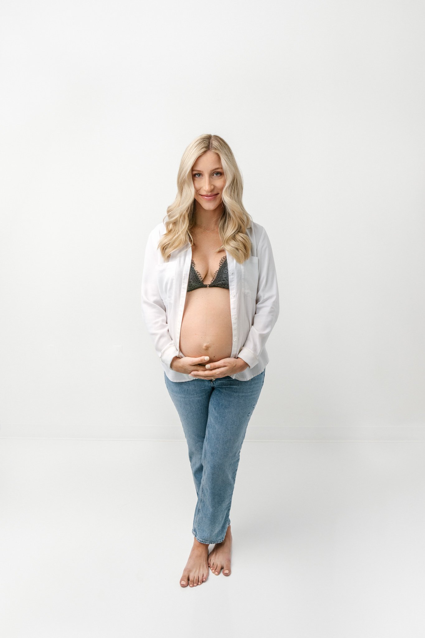  Nicole Hawkins Photography captures a maternity portrait of a woman wearing jeans and a bra with her baby bump. semi-exposed maternity #NicoleHawkinsPhotography #NicoleHawkinsMaternity #Studiomaternityportraits #NewJerseymaternity #NewYorkMaternity 