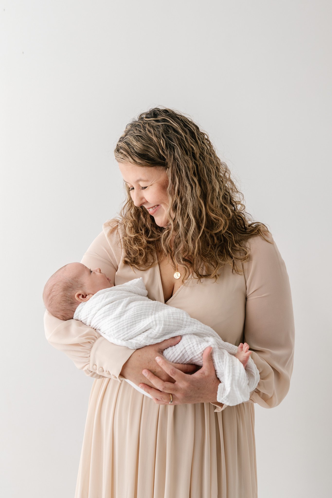  A mother with naturally curly hair holds a newborn in her arms by Nicole Hawkins Photography. newborn and her mother #NicoleHawkinsPhotography #NicoleHawkinsFamily #Newborns #MaplewoodNJ #studiofamilyportraits #modernfamilyportraits 
