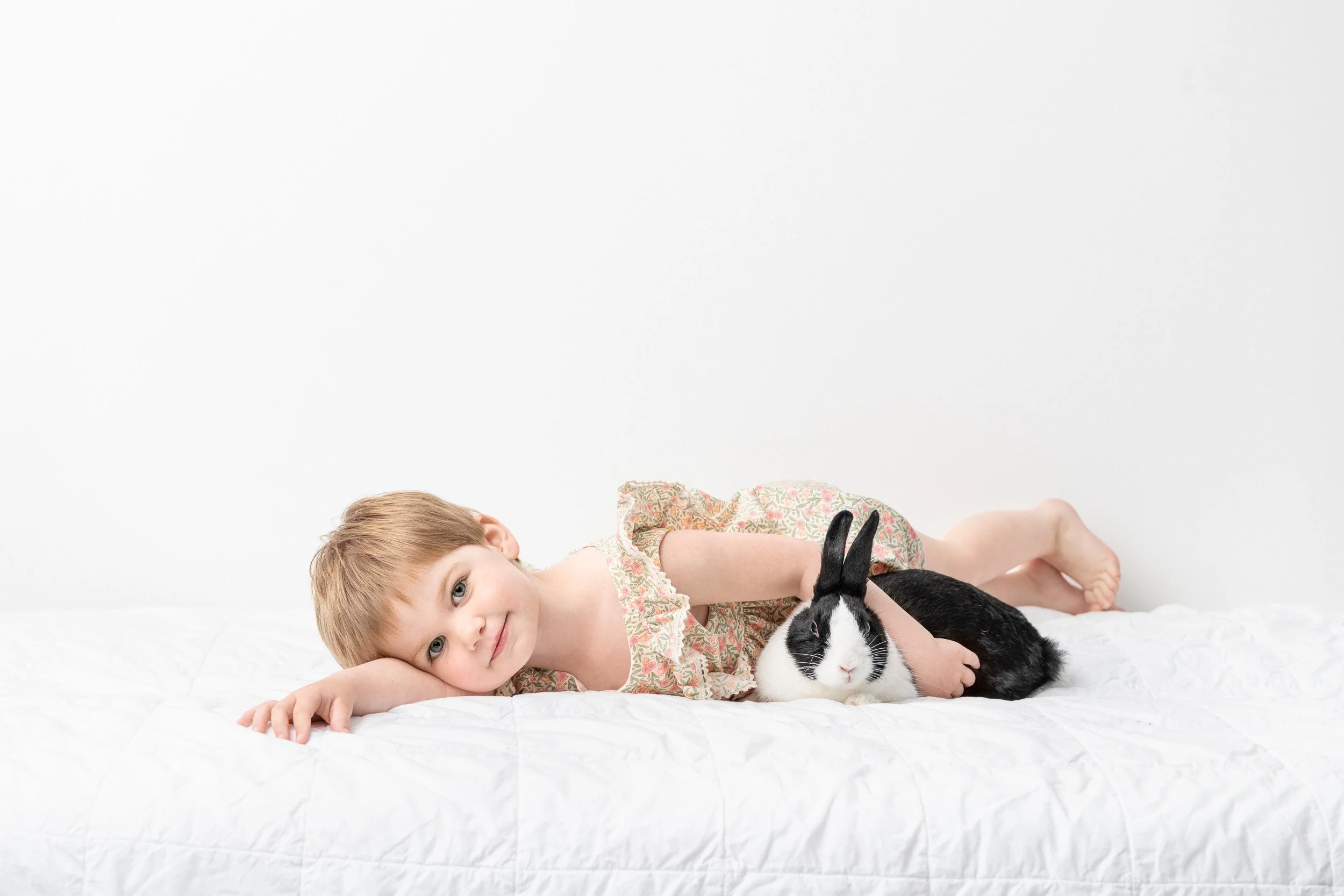  A sweet little girl lays on a bed holding her bunny by Nicole Hawkins Photography. bunny little girl portrait #NicoleHawkinsPhotography #NicoleHawkinsChildren #3rdbirthday #studioportraits #agirlandherbunny #littlegirl #milestoneportraits 