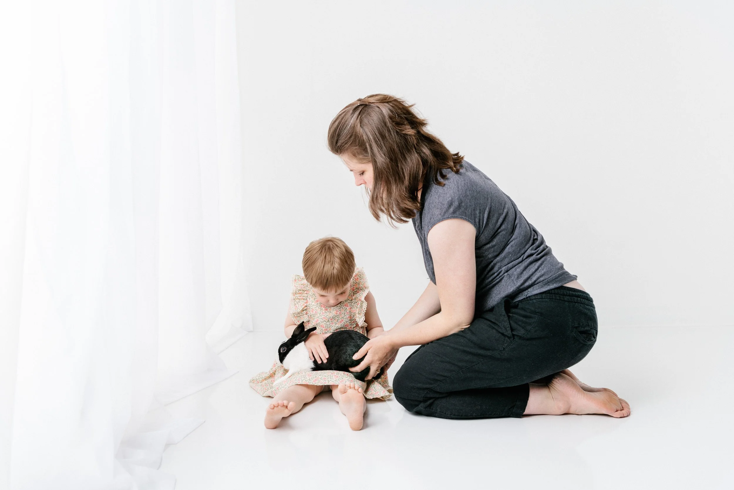  A mother hands her little girl their pet bunny to hold on her lap by Nicole Hawkins Photography. mother with child #NicoleHawkinsPhotography #NicoleHawkinsChildren #3rdbirthday #studioportrait #agirlandherbunny #littlegirl  