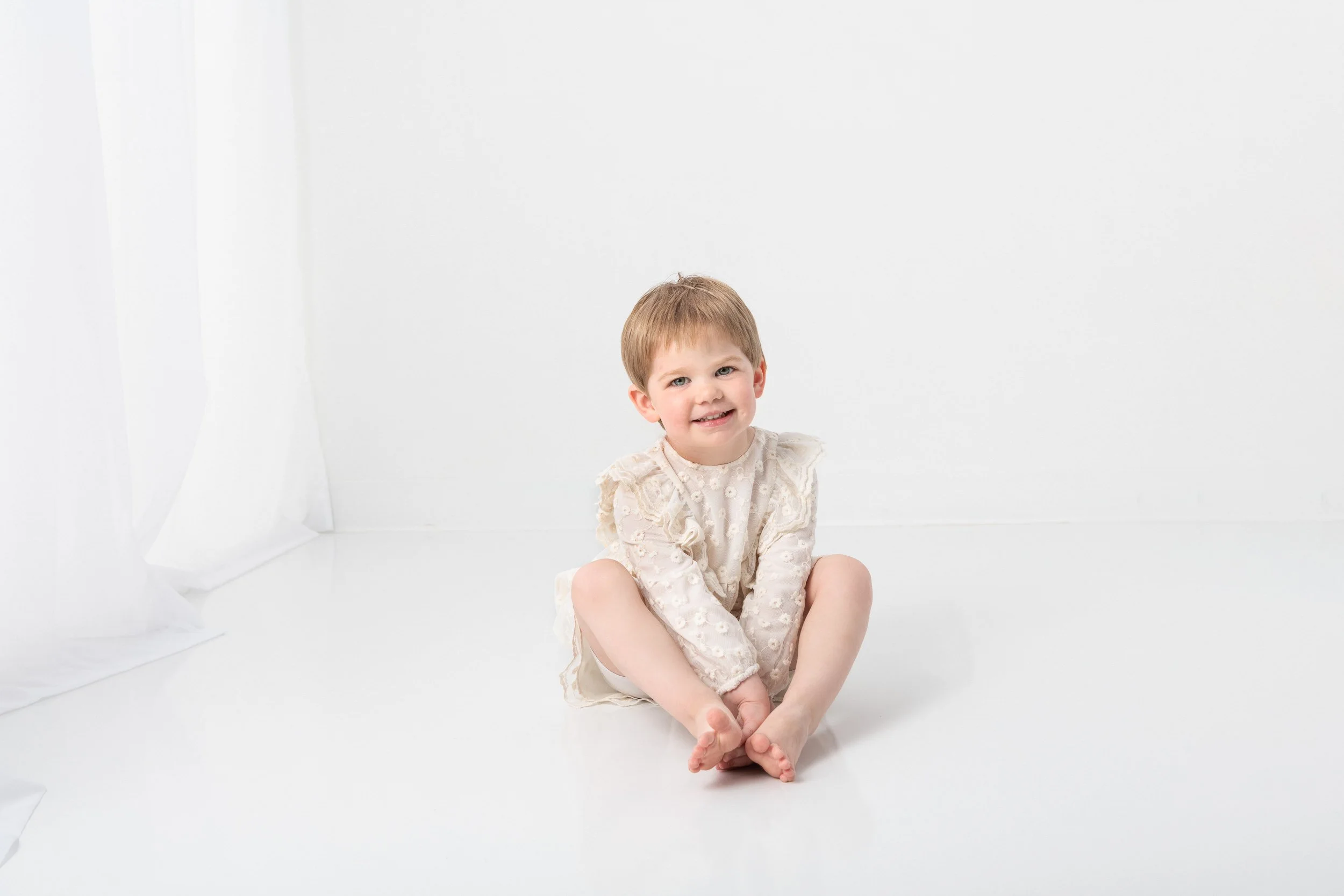  During a milestone studio portrait session, Nicole Hawkins Photography captures a little girl sitting on the floor holding her feet. red head #NicoleHawkinsPhotography #NicoleHawkinsChildren #3rdbirthday #studioportrait #agirlandherbunny #littlegirl