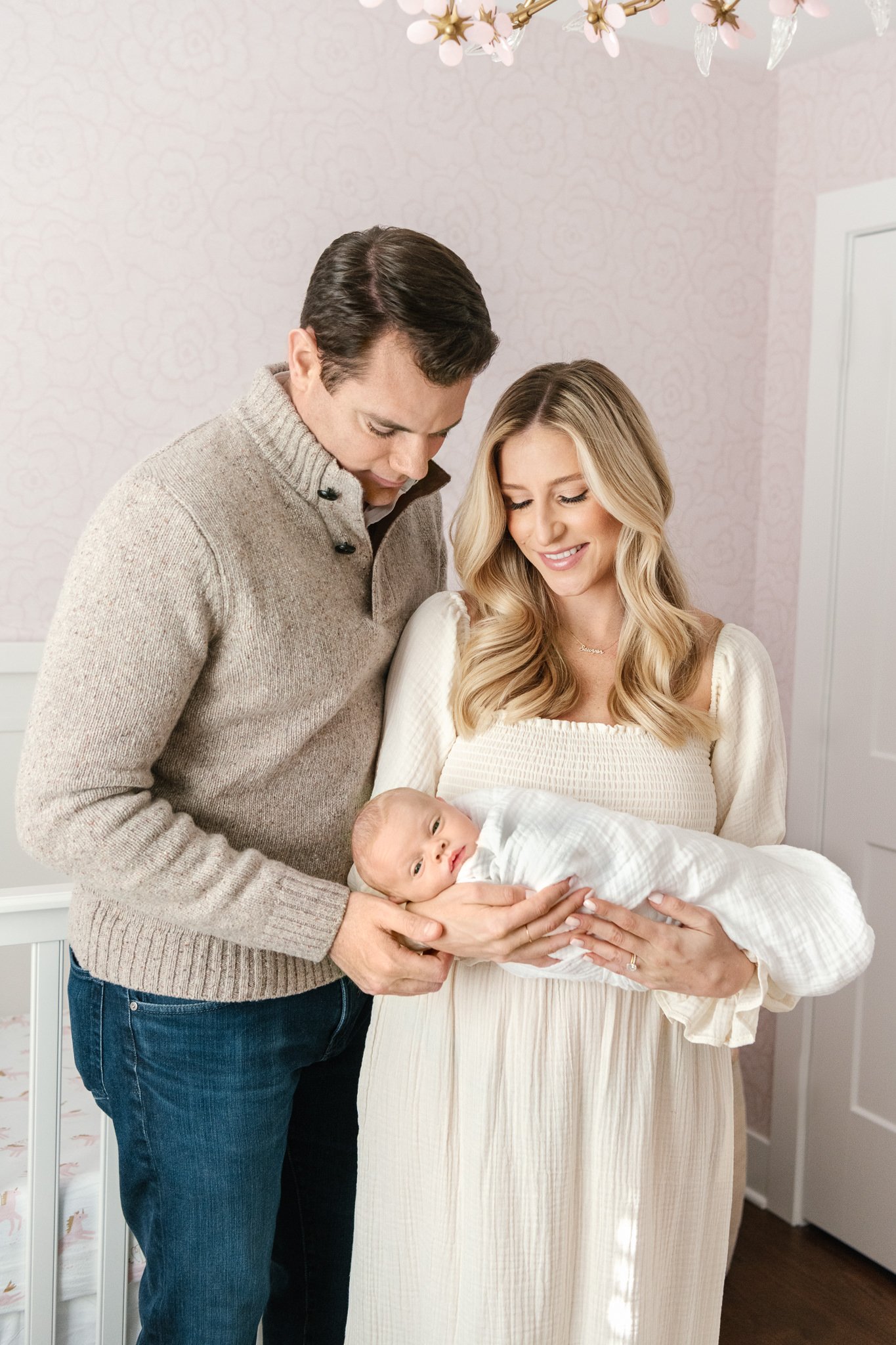  Nicole Hawkins Photography captures a mother and father with their newborn baby in the nursery. family of three new baby #NicoleHawkinsPhotography #NicoleHawkinsNewborns #InHomeNewborns #NewJerseyNewborns #NewYorkNewborns #babygirlnewborns 