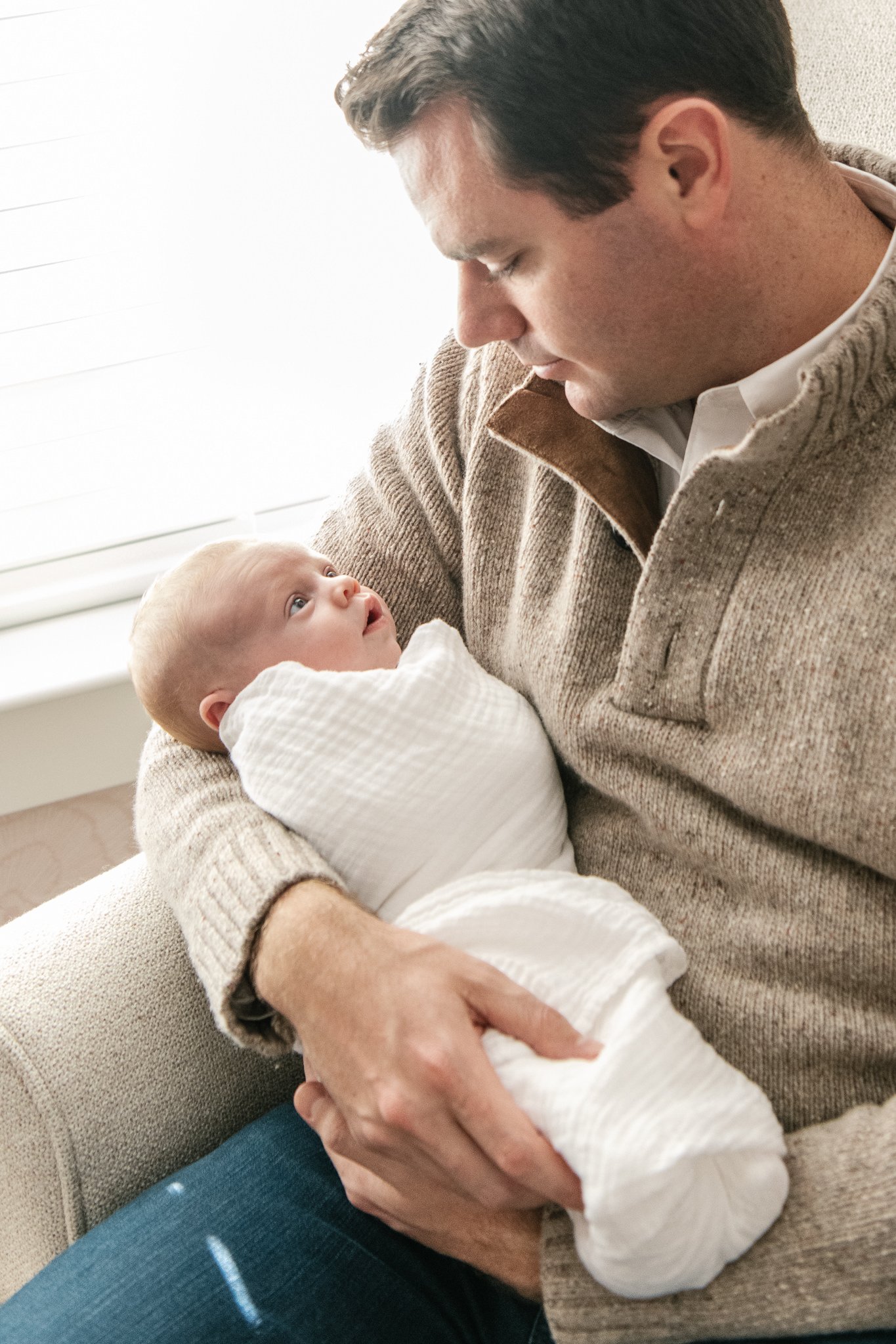  During an in-home studio newborn session, a father looks down at his baby girl by Nicole Hawkins Photography. father and baby #NicoleHawkinsPhotography #NicoleHawkinsNewborns #InHomeNewborns #NewJerseyNewborns #NewYorkNewborns #babygirlnewborns 