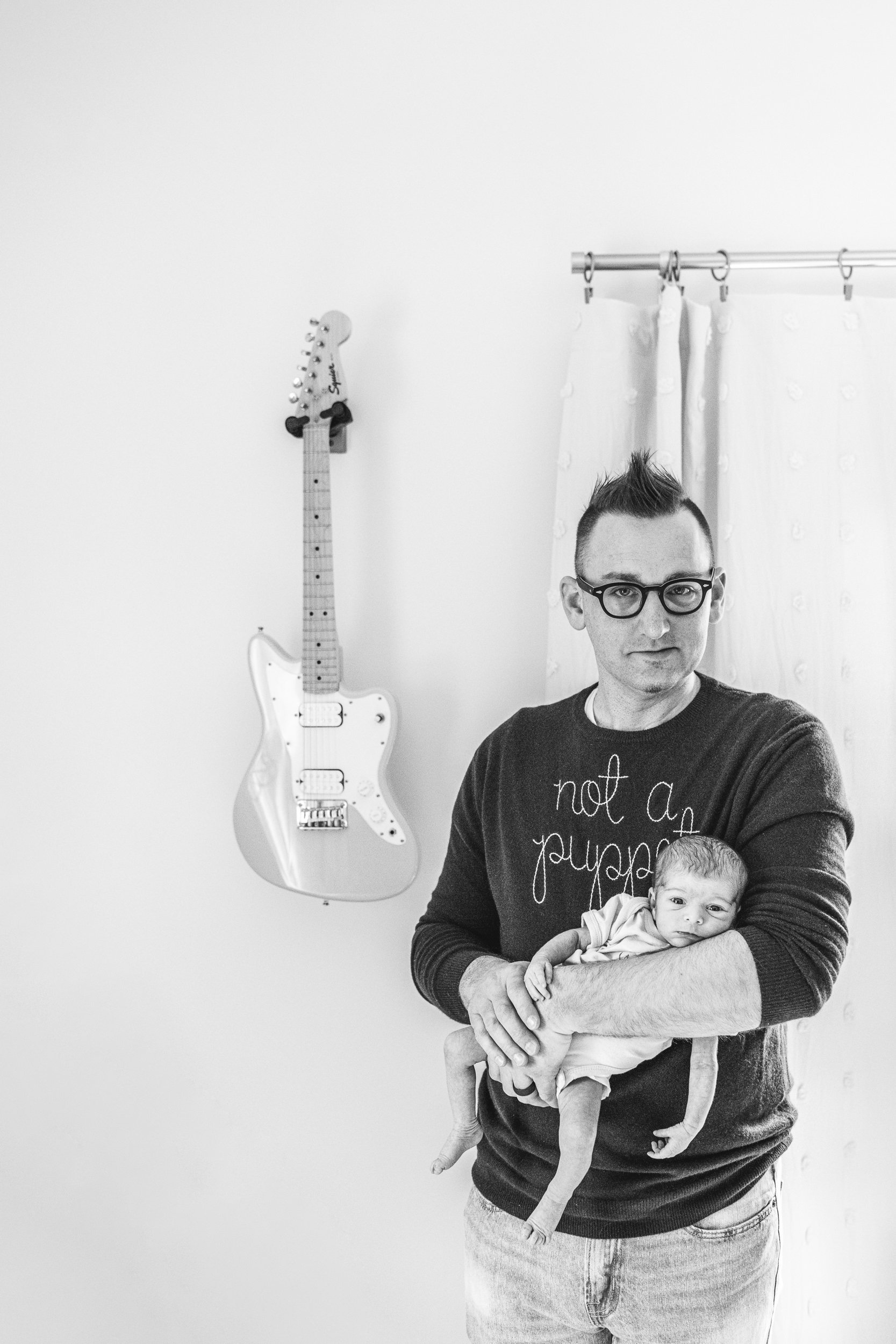  Dad holding his baby girl in front of a guitar on the wall in NJ by Nicole Hawkins Photography. guitar newborn #NicoleHawkinsPhotography #NicoleHawkinsFamily #Newborns #InHomeNewborns #NicoleHawkinsNewborns #NJnewborns #babygirl 