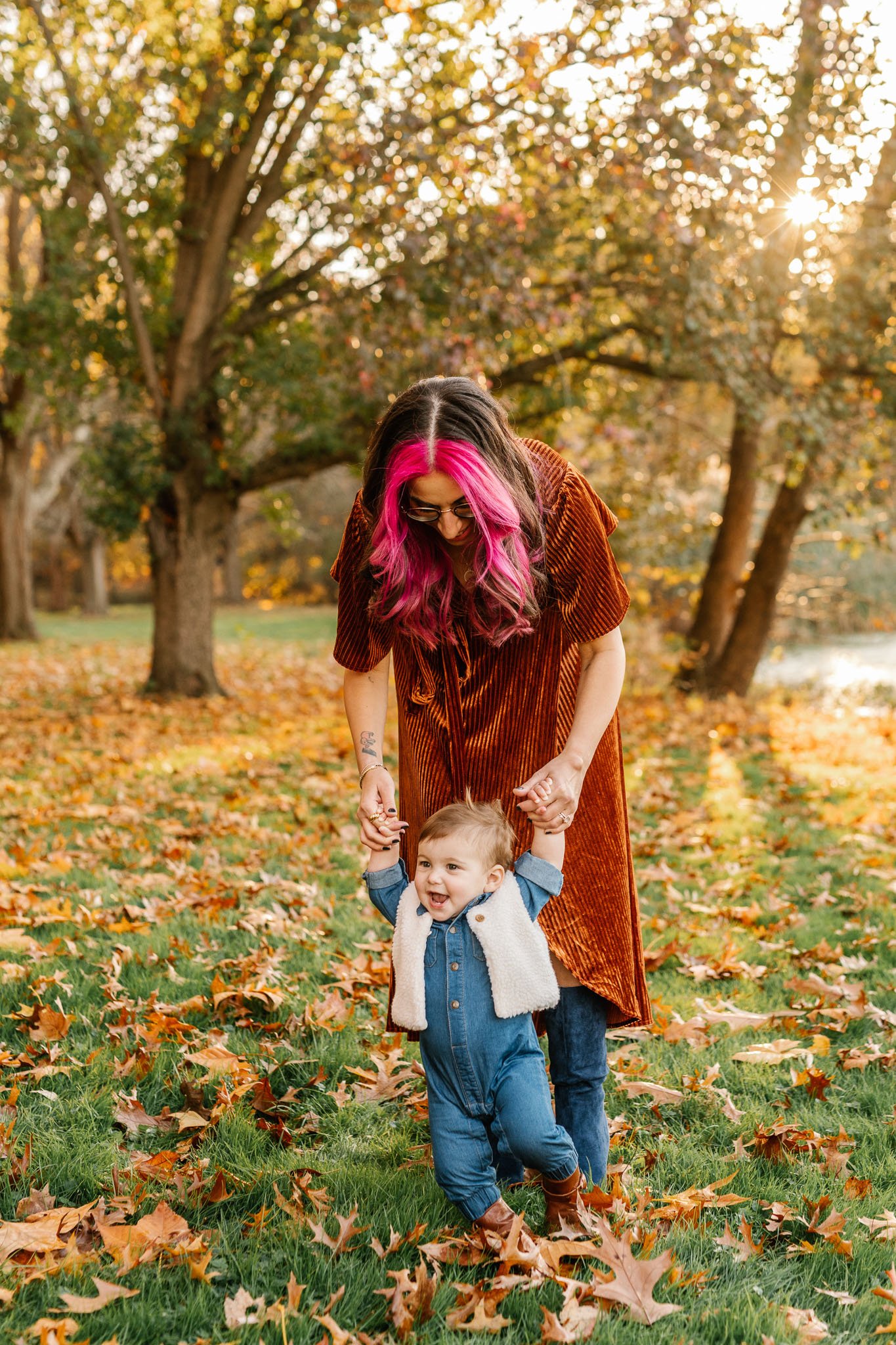  A mother helps her baby girl walk by holding her hands captured by Nicole Hawkins Photography in NJ. family portraits #NicoleHawkinsPhotography #NicoleHawkinsFamily #fallfamilyphotos #fallphotos #familyphotographerNJ #NJfallfamilypics 