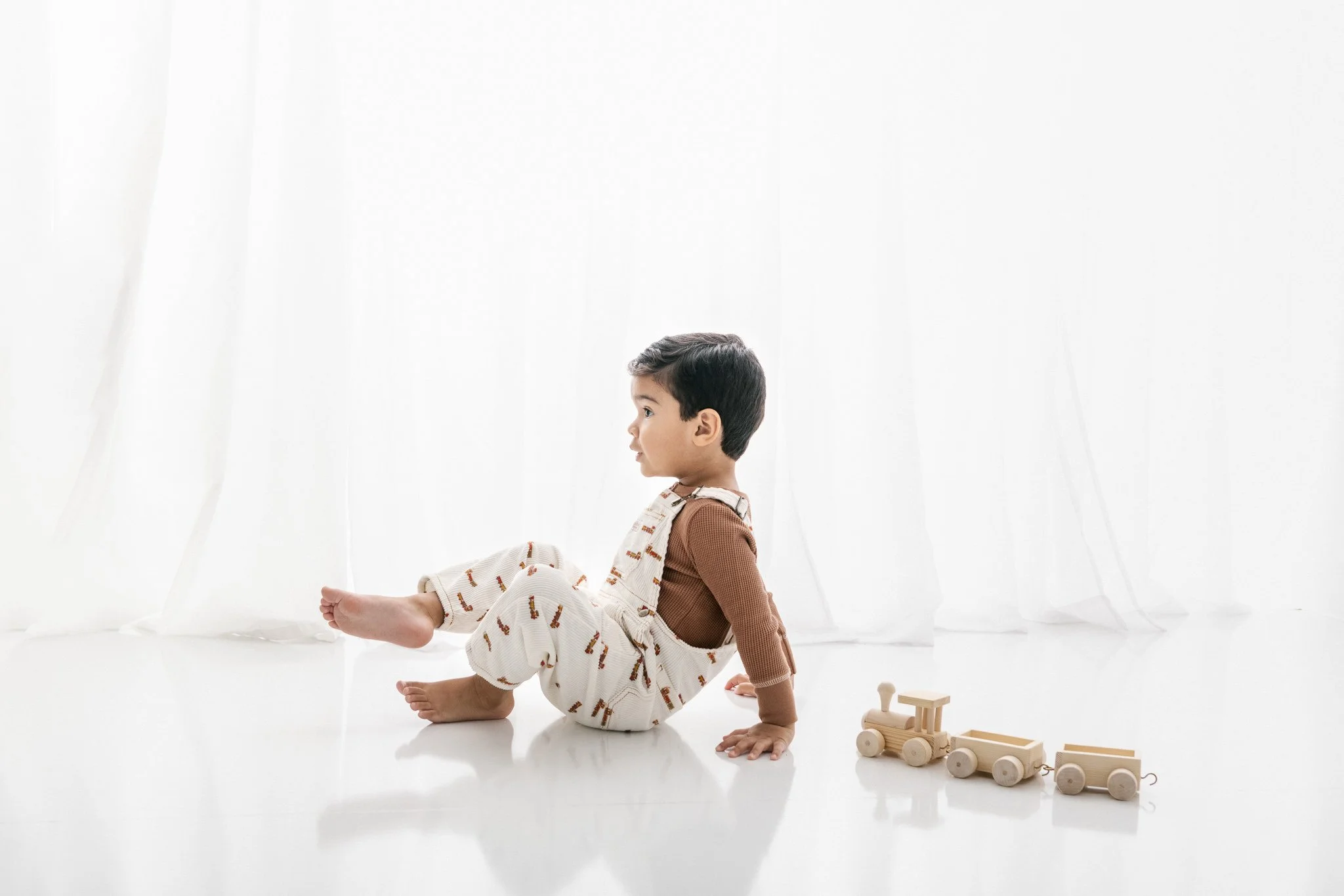  With a white background at a studio, Nicole Hawkins's Photography captures a little boy playing with a train. train toy #NicoleHawkinsPhotograaphy #NicoleHawkinsChildren #StudioBabies&amp;Children #NJphotographers #modernportraits #mom&amp;meportrai