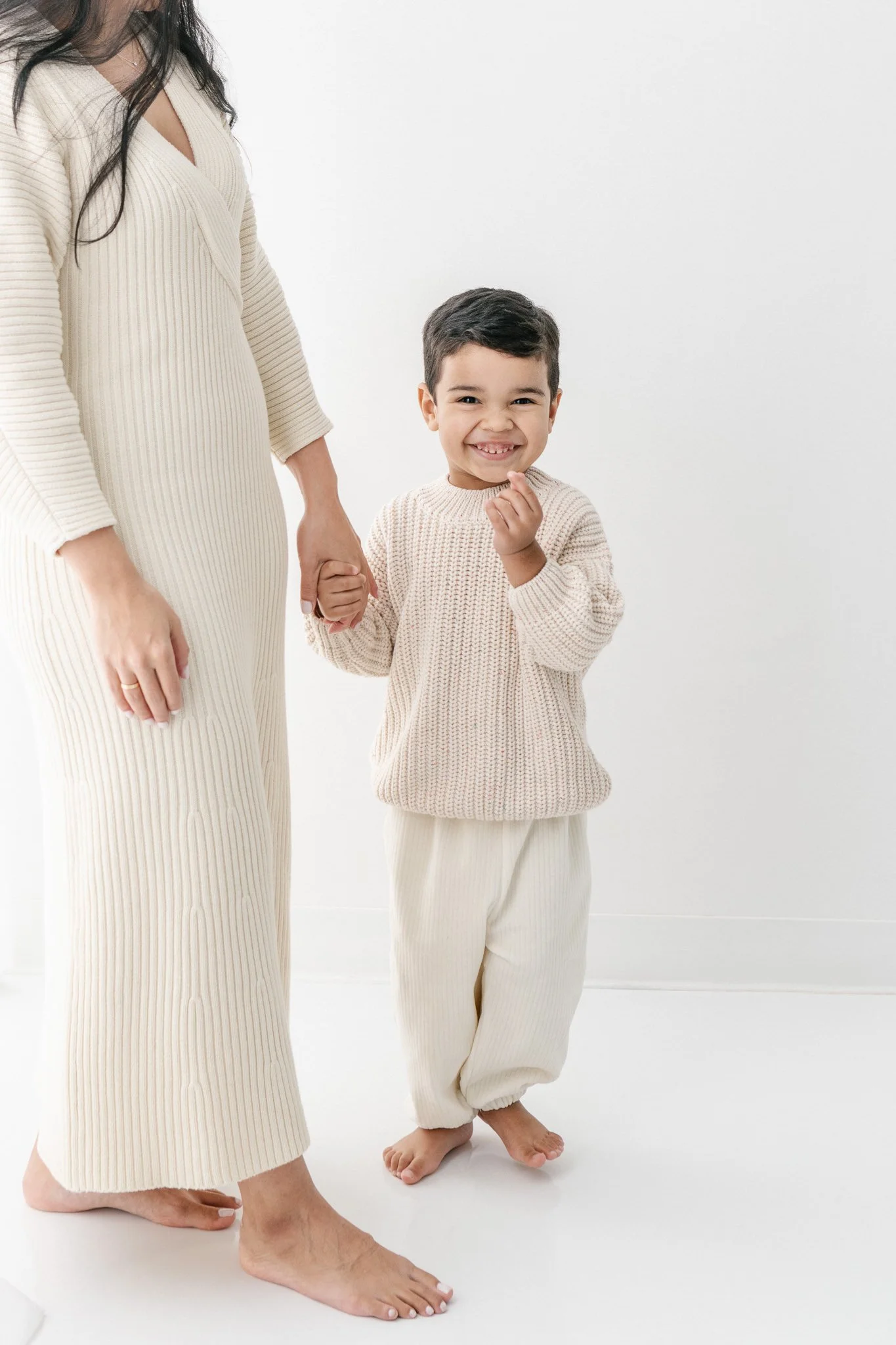  Nicole Hawkins Photography captures a boy laughing while holding his mom's hand. NJ studio portraits sweater outfits #NicoleHawkinsPhotograaphy #NicoleHawkinsChildren #StudioBabies&amp;Children #NJphotographers #modernportraits #mom&amp;meportraits 