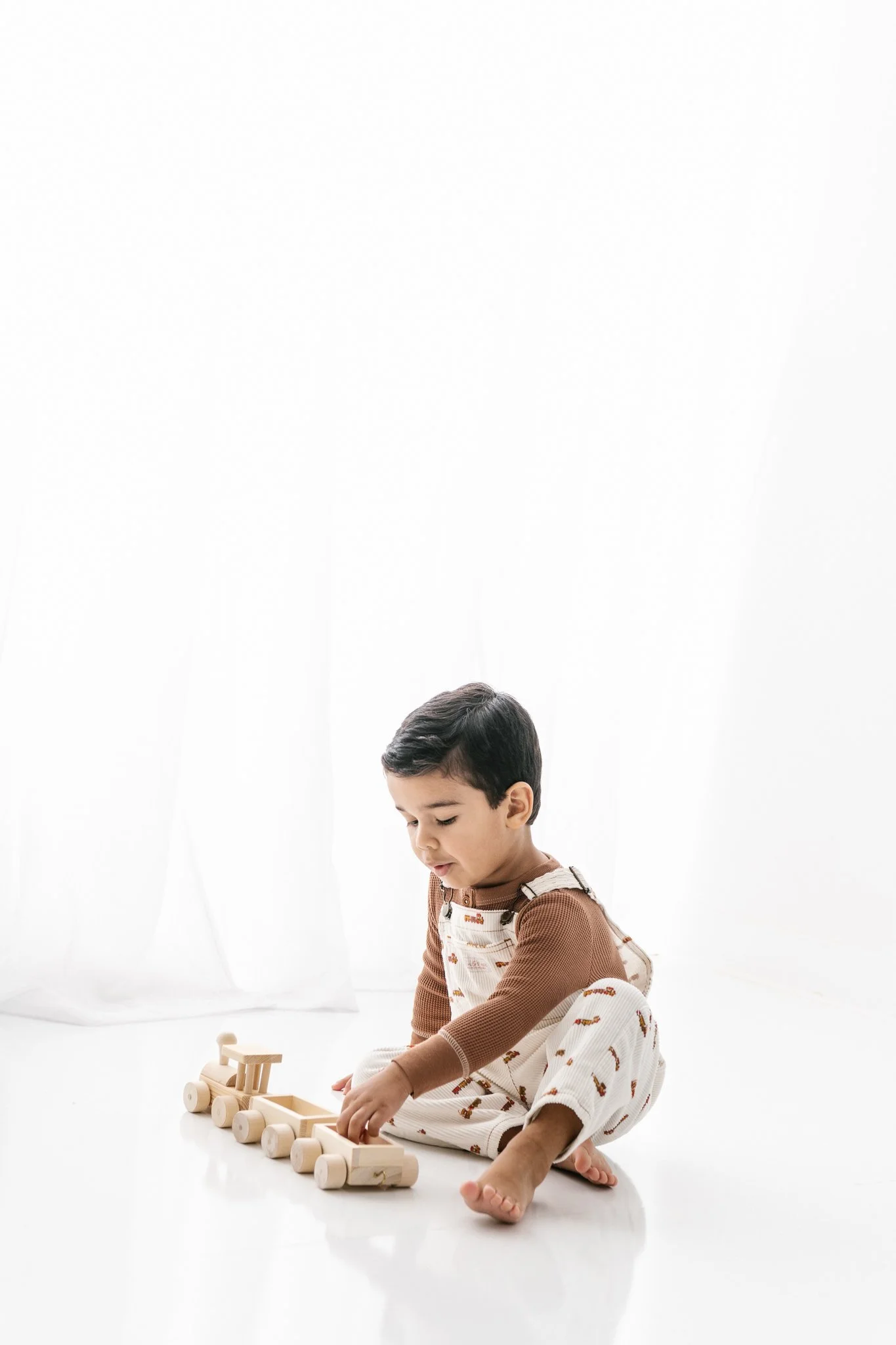  Little boy playing with an all-wooden train during a photography session with Nicole Hawkins Photography. baby boy playing #NicoleHawkinsPhotograaphy #NicoleHawkinsChildren #StudioBabies&amp;Children #NJphotographers #modernportraits #mom&amp;meport
