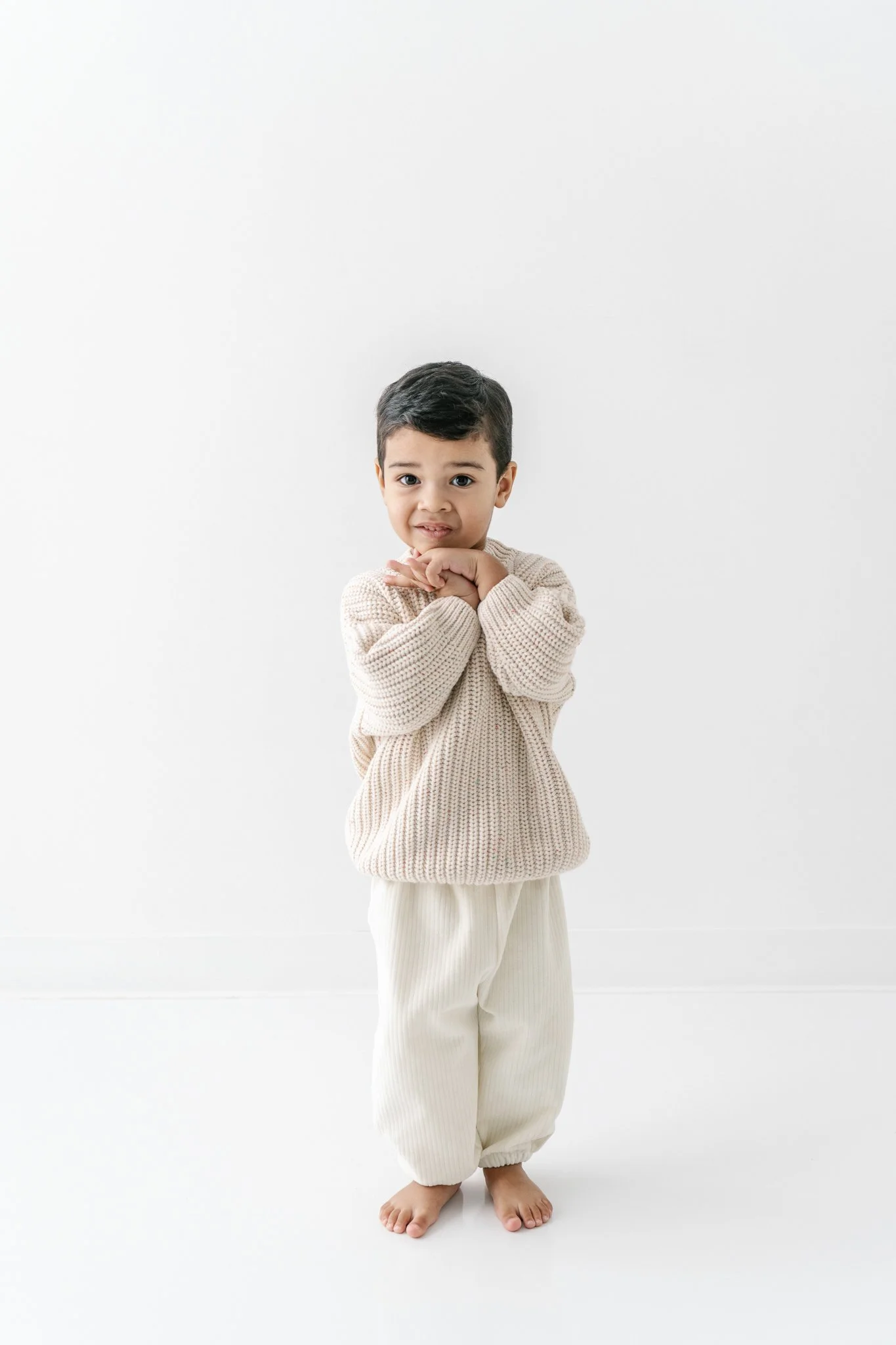  Nicole Hawkins Photography captures a little boy with his hands under his chin at a studio. all white outfit #NicoleHawkinsPhotograaphy #NicoleHawkinsChildren #StudioBabies&amp;Children #NJphotographers #modernportraits #mom&amp;meportraits  