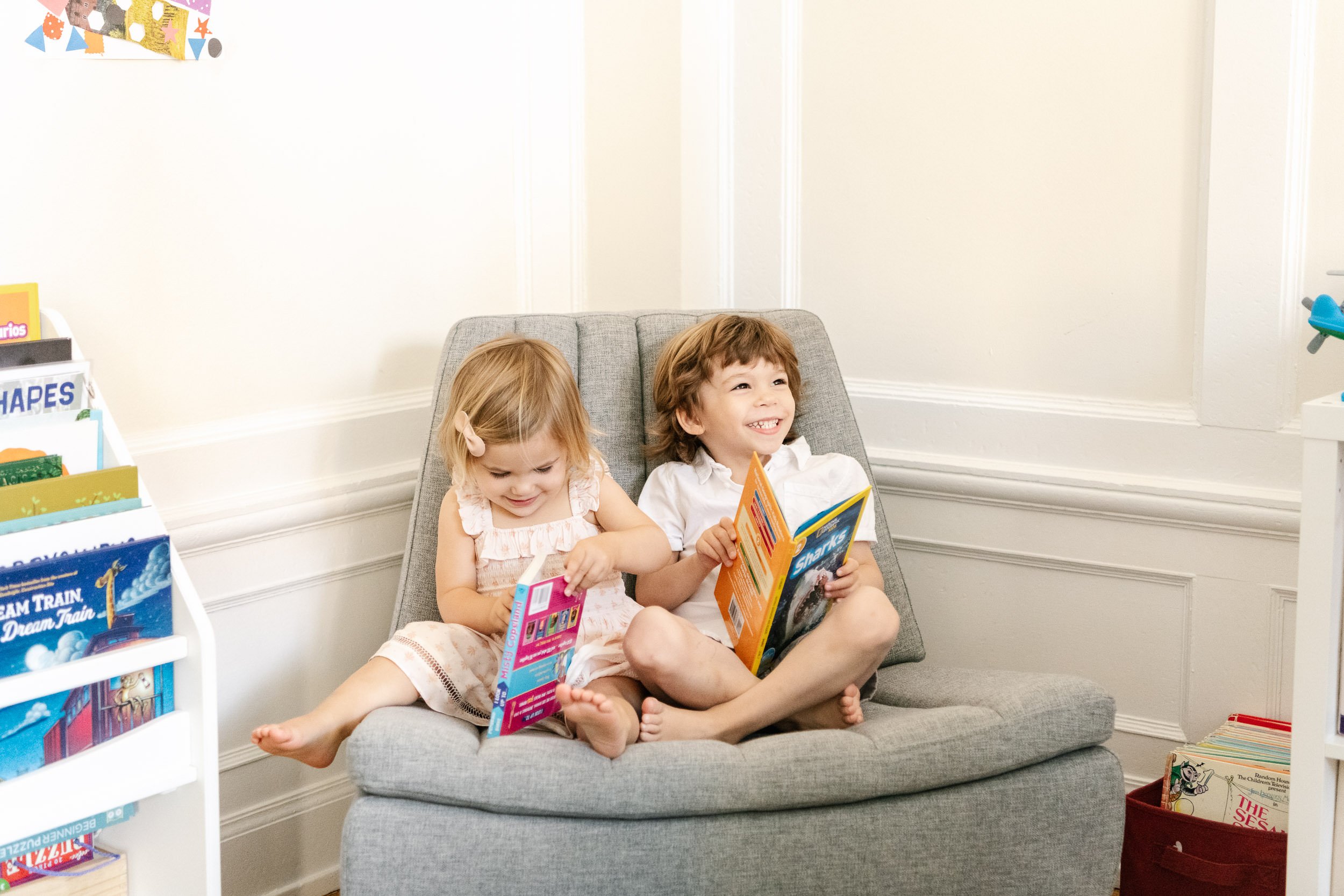  A brother and sister sit on a chair together and read stories by Nicole Hawkins Photography. brother and sister #NicoleHawkinsPhotograaphy #NicoleHawkinsChildren #NewYorkPortraits #KidsinNewYork #ChildrensPortraits #lifestyleportraits 