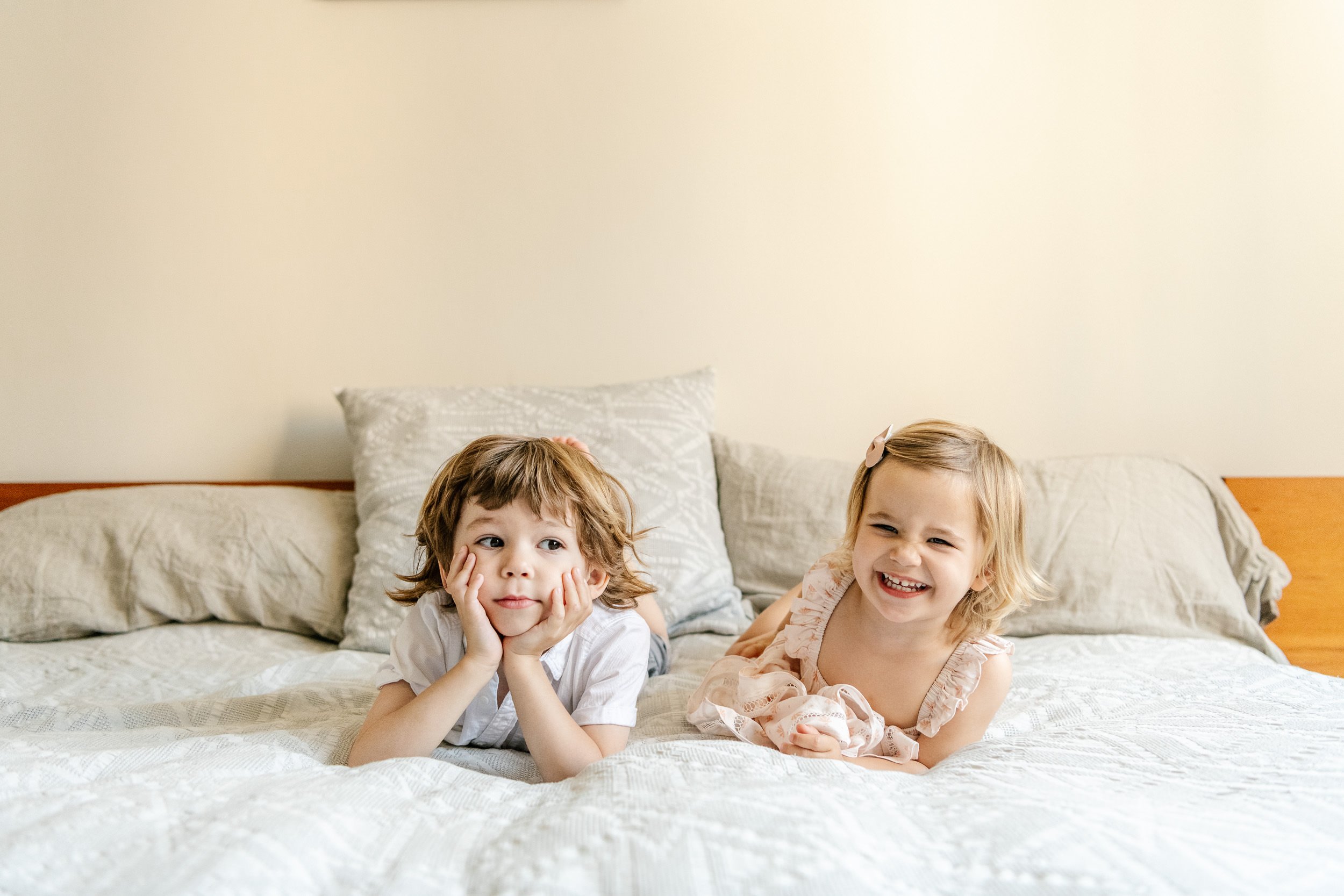  Two little kids laying on a bed together laughing by Nicole Hawkins Photography. modern simple portraits for kids #NicoleHawkinsPhotograaphy #NicoleHawkinsChildren #NewYorkPortraits #KidsinNewYork #ChildrensPortraits #lifestyleportraits 