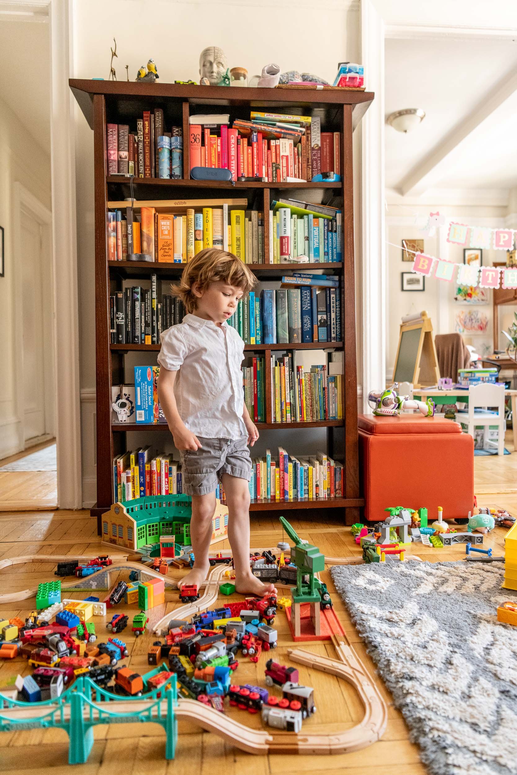  An authentic portrait of a boy playing at his house in NYC with a colorful bookcase behind him by Nicole Hawkins Photography. #NicoleHawkinsPhotograaphy #NicoleHawkinsChildren #NewYorkPortraits #KidsinNewYork #ChildrensPortraits #lifestyleportraits 