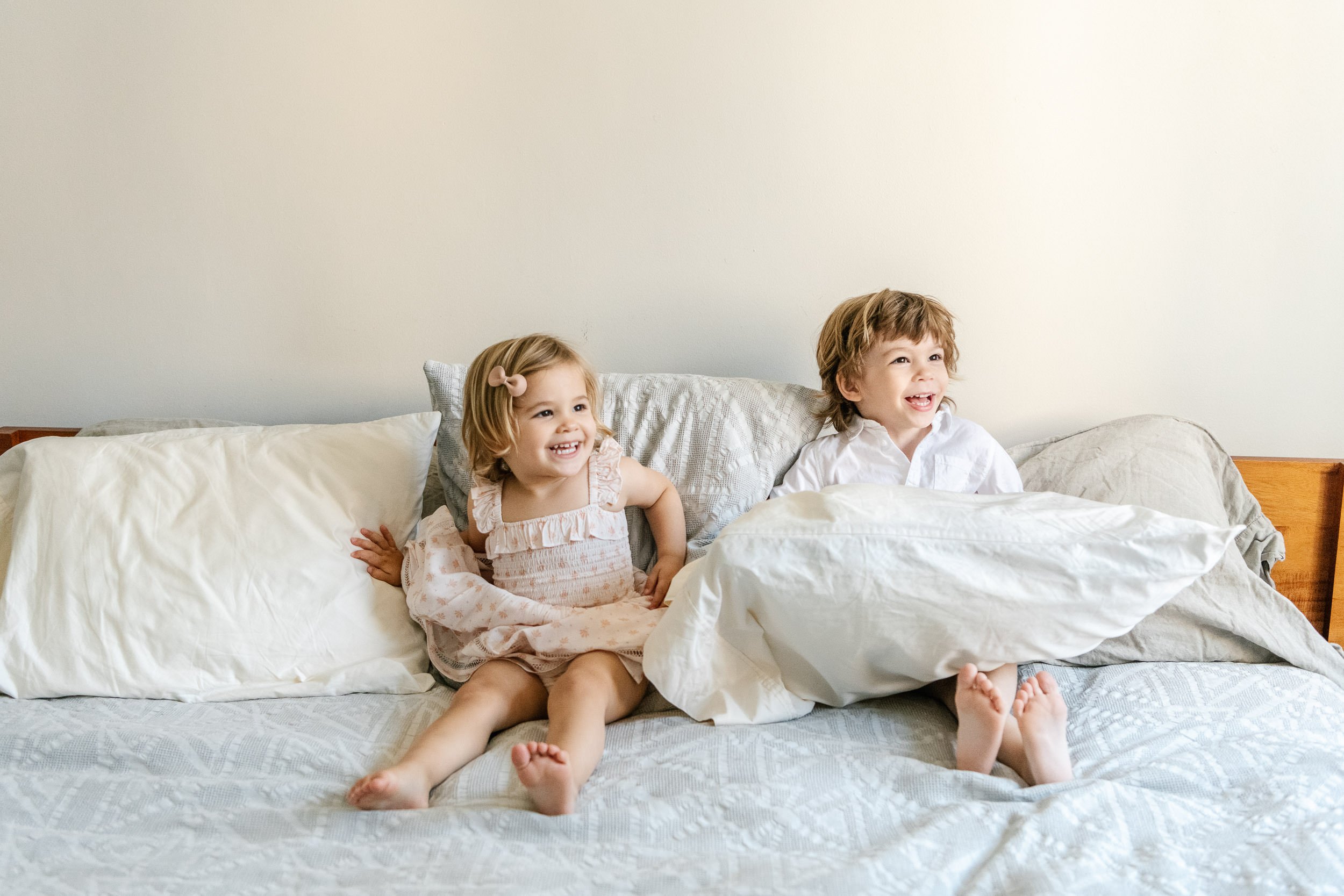  A brother and sister sit on a bed and laugh captured by Nicole Hawkins Photography. in home portraits children #NicoleHawkinsPhotograaphy #NicoleHawkinsChildren #NewYorkPortraits #KidsinNewYork #ChildrensPortraits #lifestyleportraits 