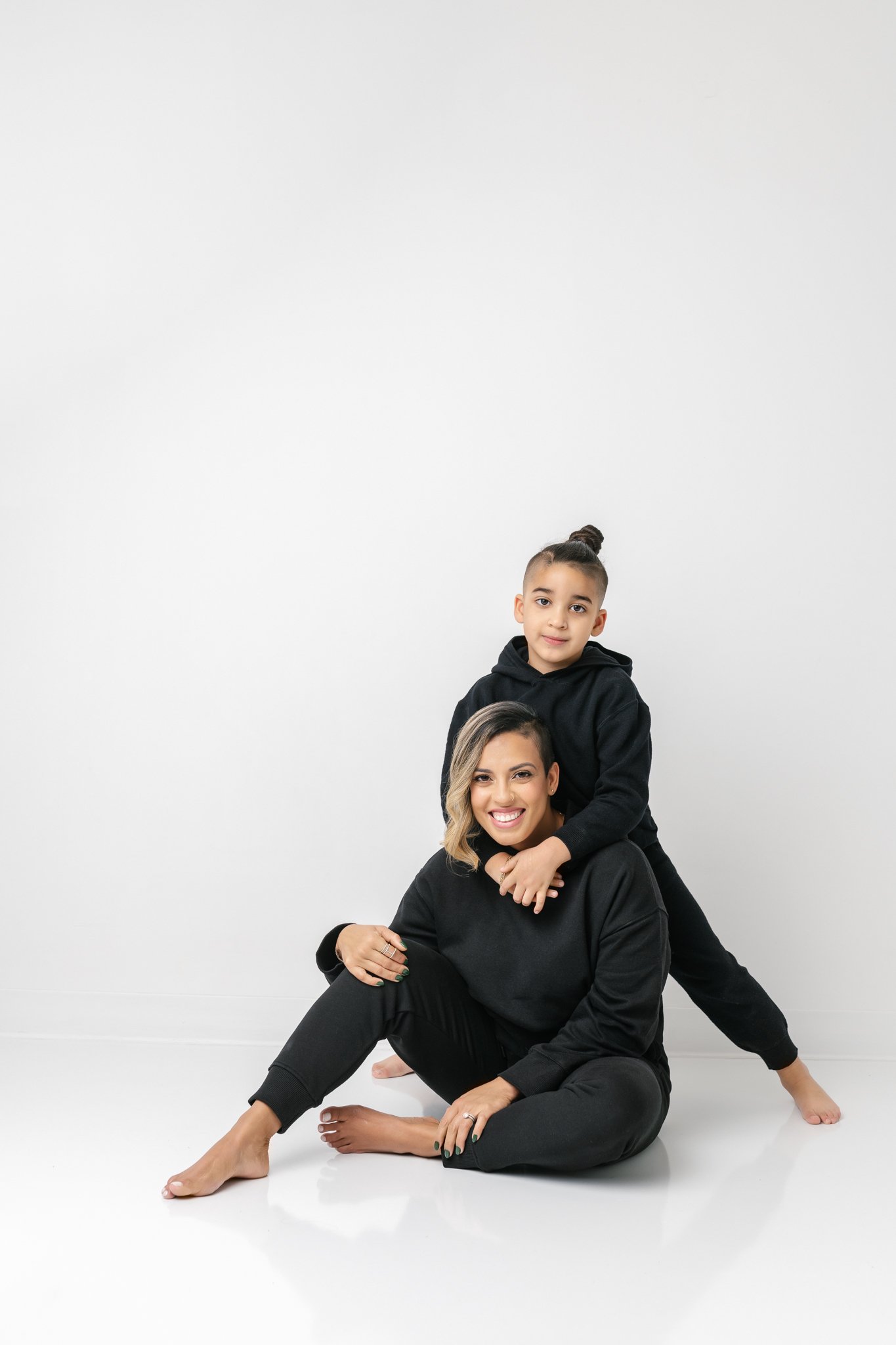  A little boy wraps his arms around his mother's neck during a family session with Nicole Hawkins Photography. studio #NicoleHawkinsPhotograaphy #NicoleHawkinsFamilies #Modernfamilypictures #studioportraits #matchingfamilyoutfits #NJphotographer 