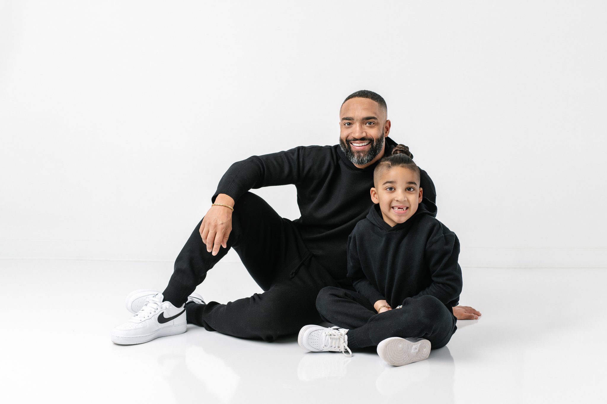  Nicole Hawkins Photography captures a modern studio portrait of a father and son sitting together. simple classic #NicoleHawkinsPhotograaphy #NicoleHawkinsFamilies #Modernfamilypictures #studioportraits #matchingfamilyoutfits #NJphotographer 