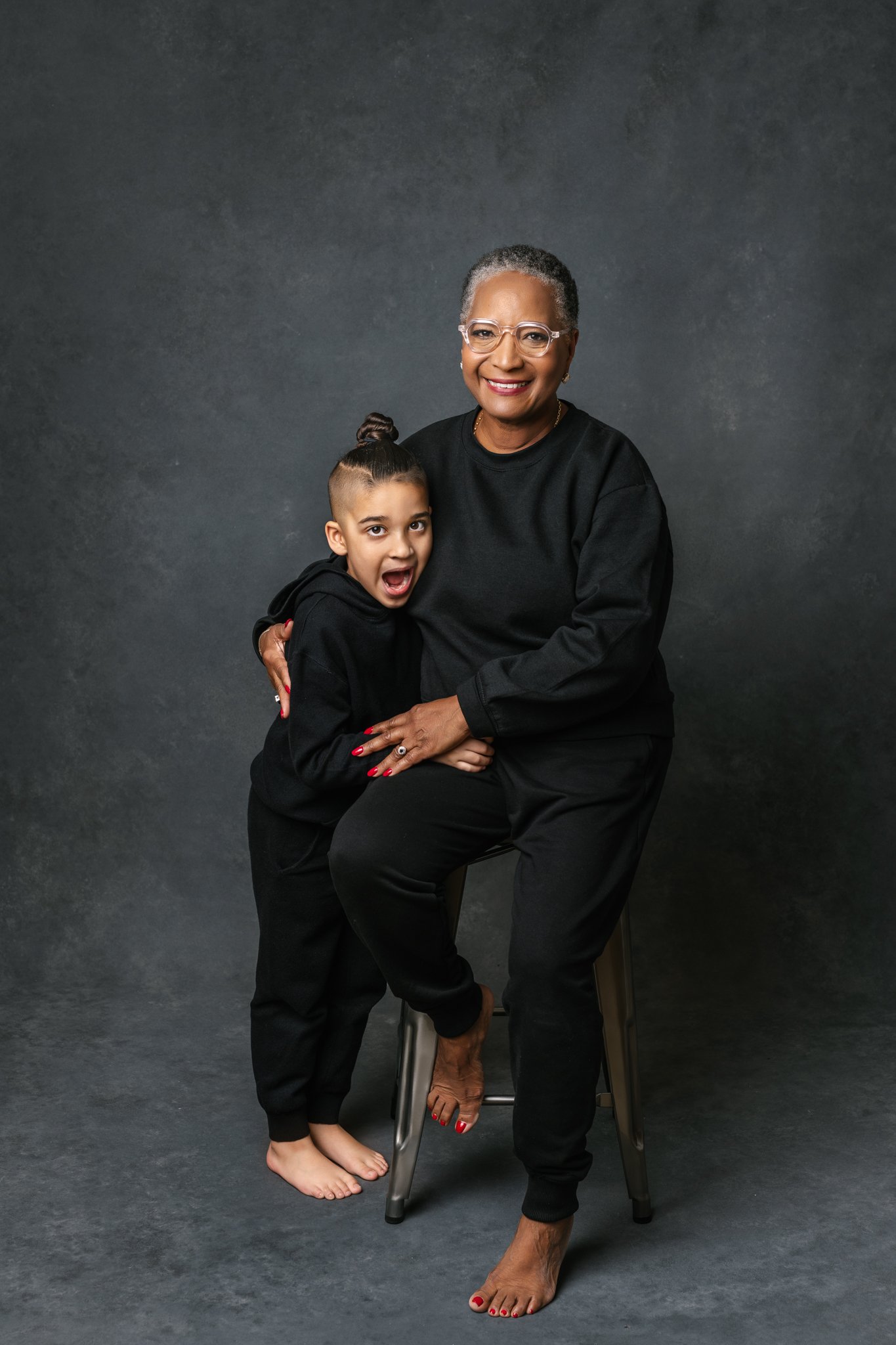  Wearing matching black sweatsuits a grandma and grandson hug by Nicole Hawkins Photography. black outfits #NicoleHawkinsPhotograaphy #NicoleHawkinsFamilies #Modernfamilypictures #studioportraits #matchingfamilyoutfits #NJphotographer 