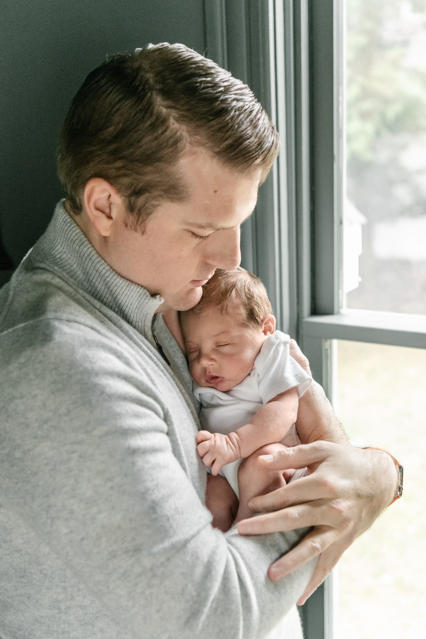  A father snuggles his newborn baby girl by Nicole Hawkins Photography in New Jersey. father with his newborn baby girl in white #NicoleHawkinsPhotography #NicoleHawkinsNewborns #MontclairNewbornPhotographer #InHomeNewborns #NJNewborns #Babygirl #New