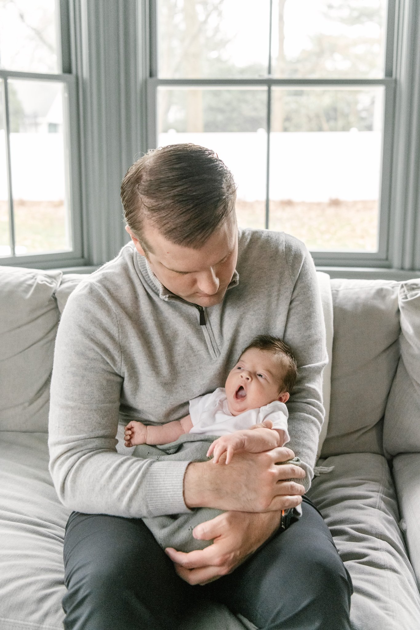  During an in-home newborn session in Montclair, NJ Nicole Hawkins Photography captures a baby yawning in her father's arms. yawning baby #NicoleHawkinsPhotography #NicoleHawkinsNewborns #MontclairNewbornPhotographer #InHomeNewborns #NJNewborns #Baby