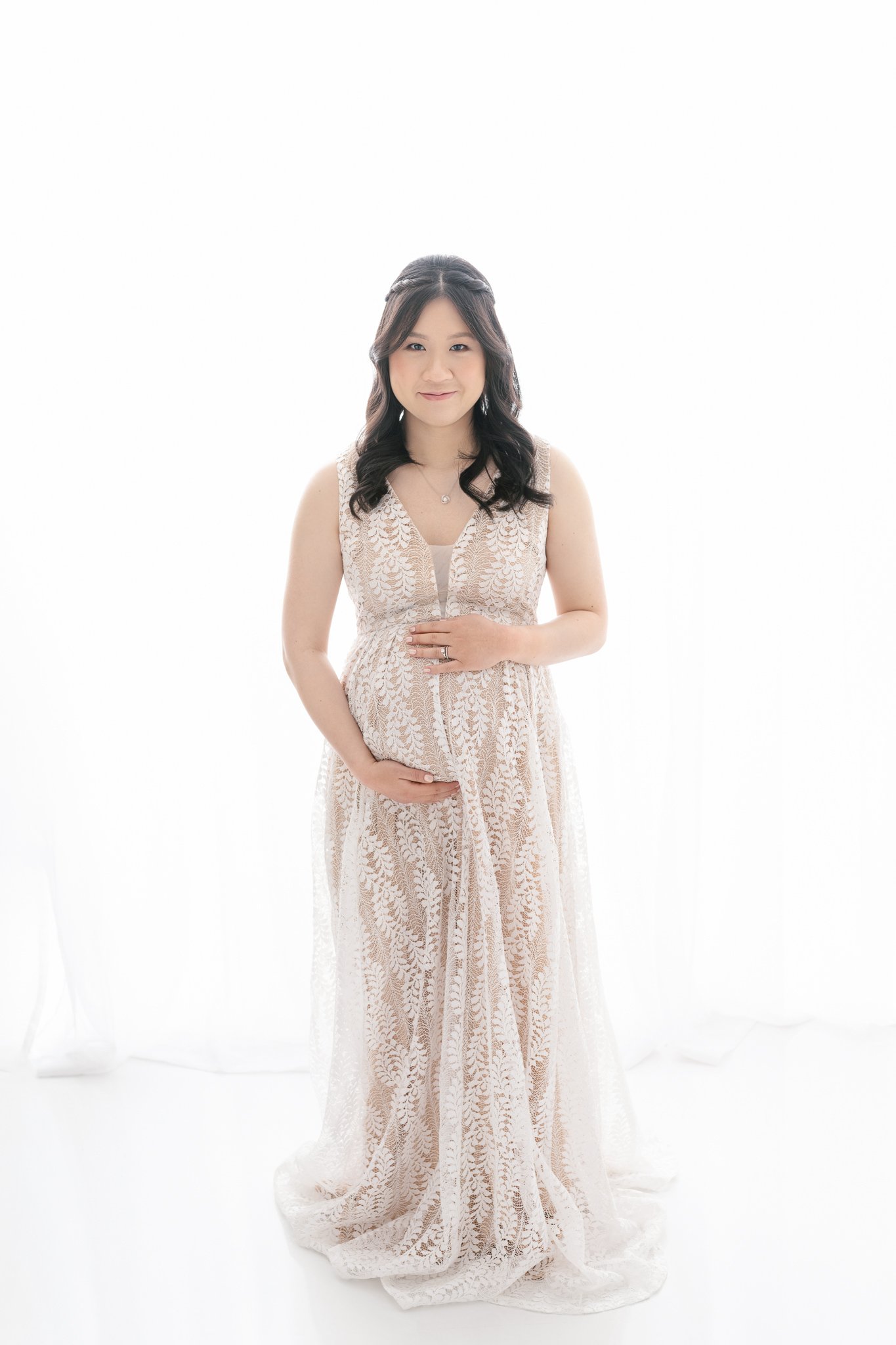  A new mother holds her maternity bump in her arms and looks forward in a studio by Nicole Hawkins Photography. maternity style ideas flattering maternity gowns #NicoleHawkinsPhotography #NicoleHawkinsMaternity #MaternityPhotography #Maternitystyle #