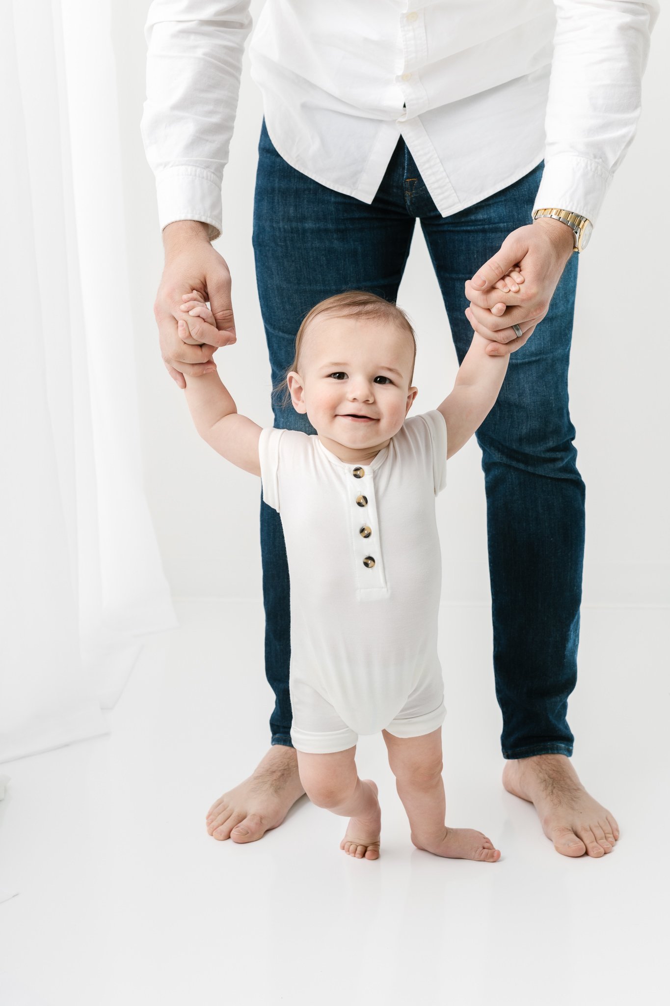  Studio baby portraits for a little boy smiling as he walks around with his father by Nicole Hawkins Photography. baby boy walking white romper baby boy studio outfits baby #NicoleHawkinsPhotography #NicoleHawkinsBabies #FirstBirthdayPhotography #Stu