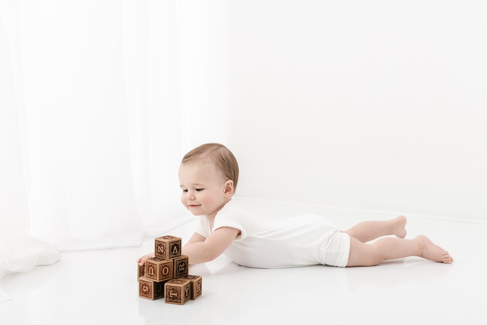  During a first birthday portrait aa little boy plays with a pile of blocks with Nicole Hawkins Photography. first birthday portraits at a studio children studio portraits #NicoleHawkinsPhotography #NicoleHawkinsBabies #FirstBirthdayPhotography #Stud