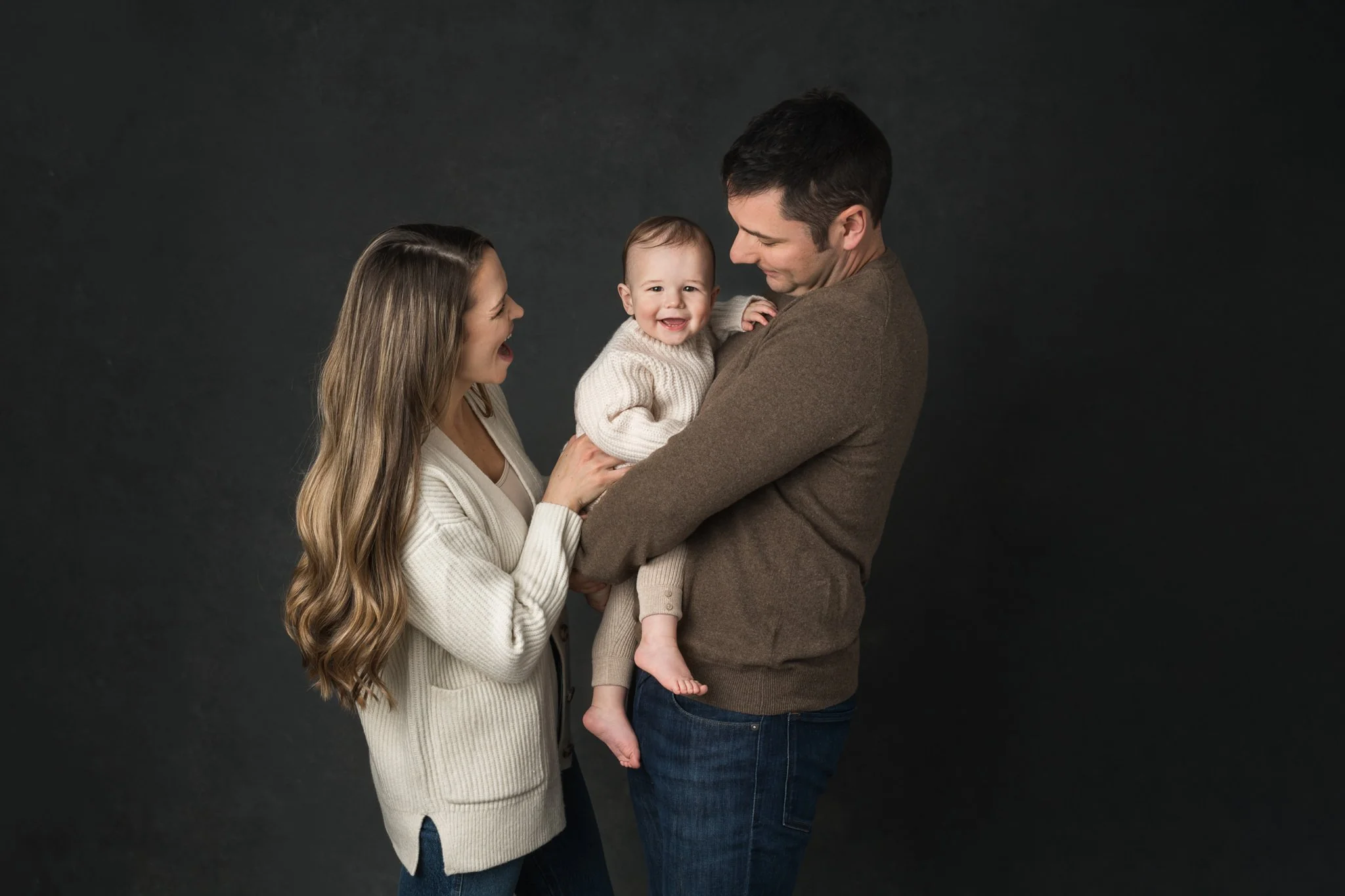  A mother tickles her baby boy making him laugh by Nicole Hawkins Photography. mother tickles baby boy family of three #NicoleHawkinsPhotography #NicoleHawkinsBabies #FirstBirthdayPhotography #StudioFamilyPortraits #NJBabies #FirstBirthday #StudioBab