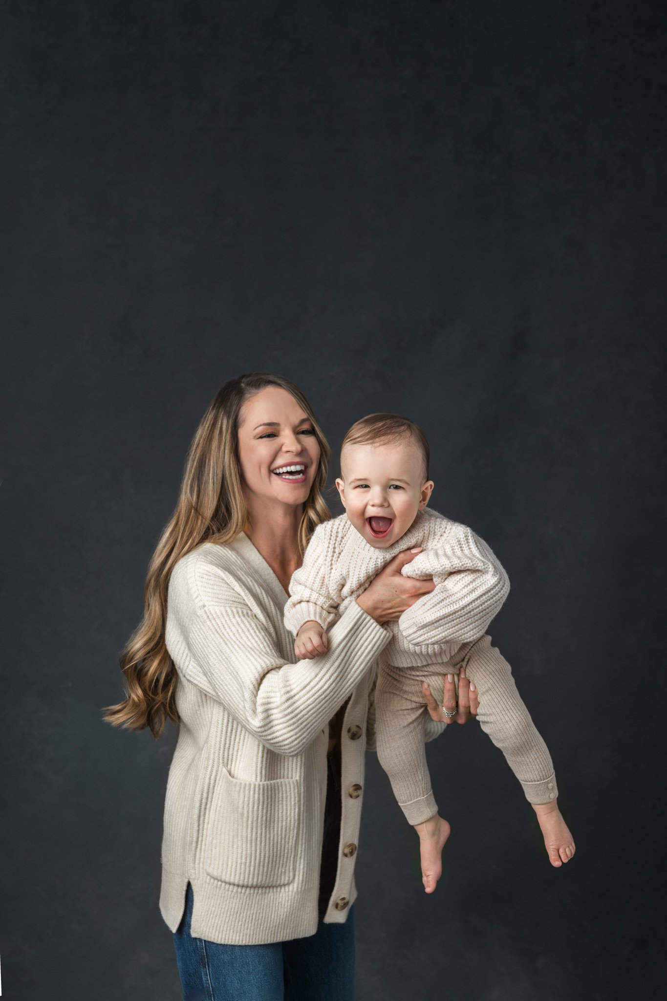  A mother zooms her baby boy around making them both laugh by Nicole Hawkins Photography. candid portrait of a mother and baby #NicoleHawkinsPhotography #NicoleHawkinsBabies #FirstBirthdayPhotography #StudioFamilyPortraits #NJBabies #FirstBirthday #S