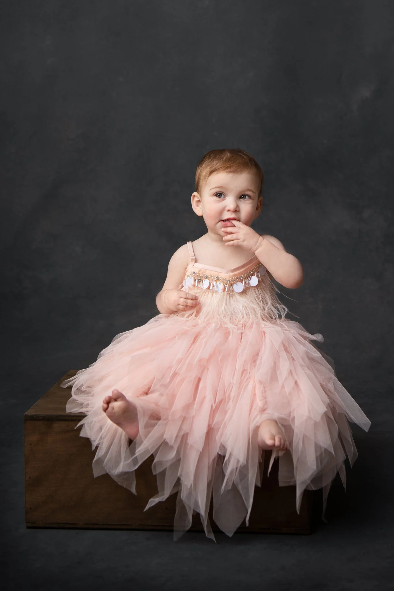  High-end child and baby photographer Nicole Hawkins Photography captures a little girl in a pink dress with a black studio backdrop. black and white studio high end #NicoleHawkinsPhotography #NicoleHawkinsBabies&amp;Children #FirstBirthdayPhotograph