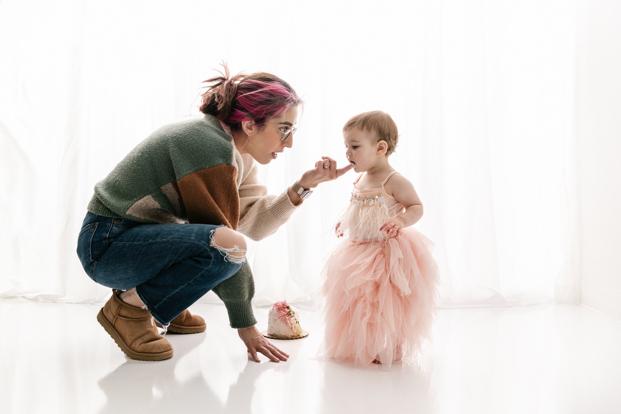  A mother kneels down next to her toddler baby girl by Nicole Hawkins Photography in New Jersey. mother and baby studio first birthday #NicoleHawkinsPhotography #NicoleHawkinsBabies&amp;Children #FirstBirthdayPhotography #StudioPhotography #Smashcake