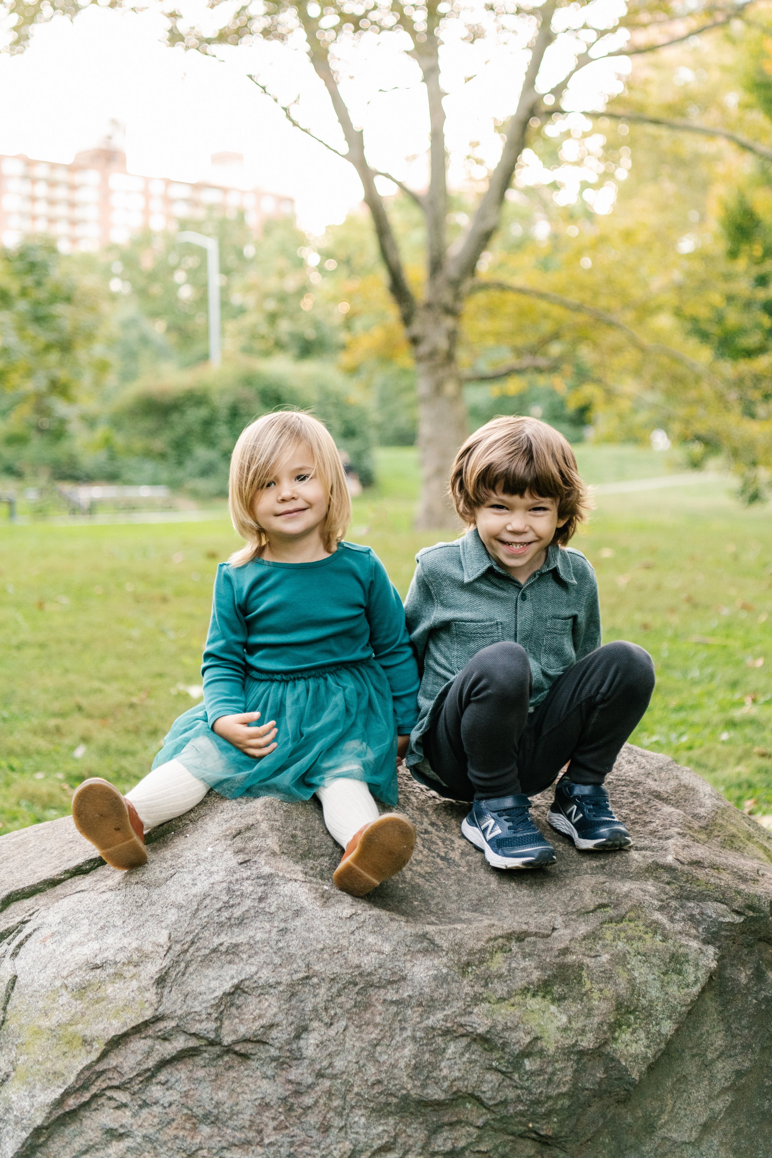  Two little kids sit on a giant rock in Central Park by Nicole Hawkins Photography. portraits outdoors NY family photographers siblings photography #NicoleHawkinsPhotography #NicoleHawkinsFamilies #NJphotographers #familyphotos #CentralParkPhotograph